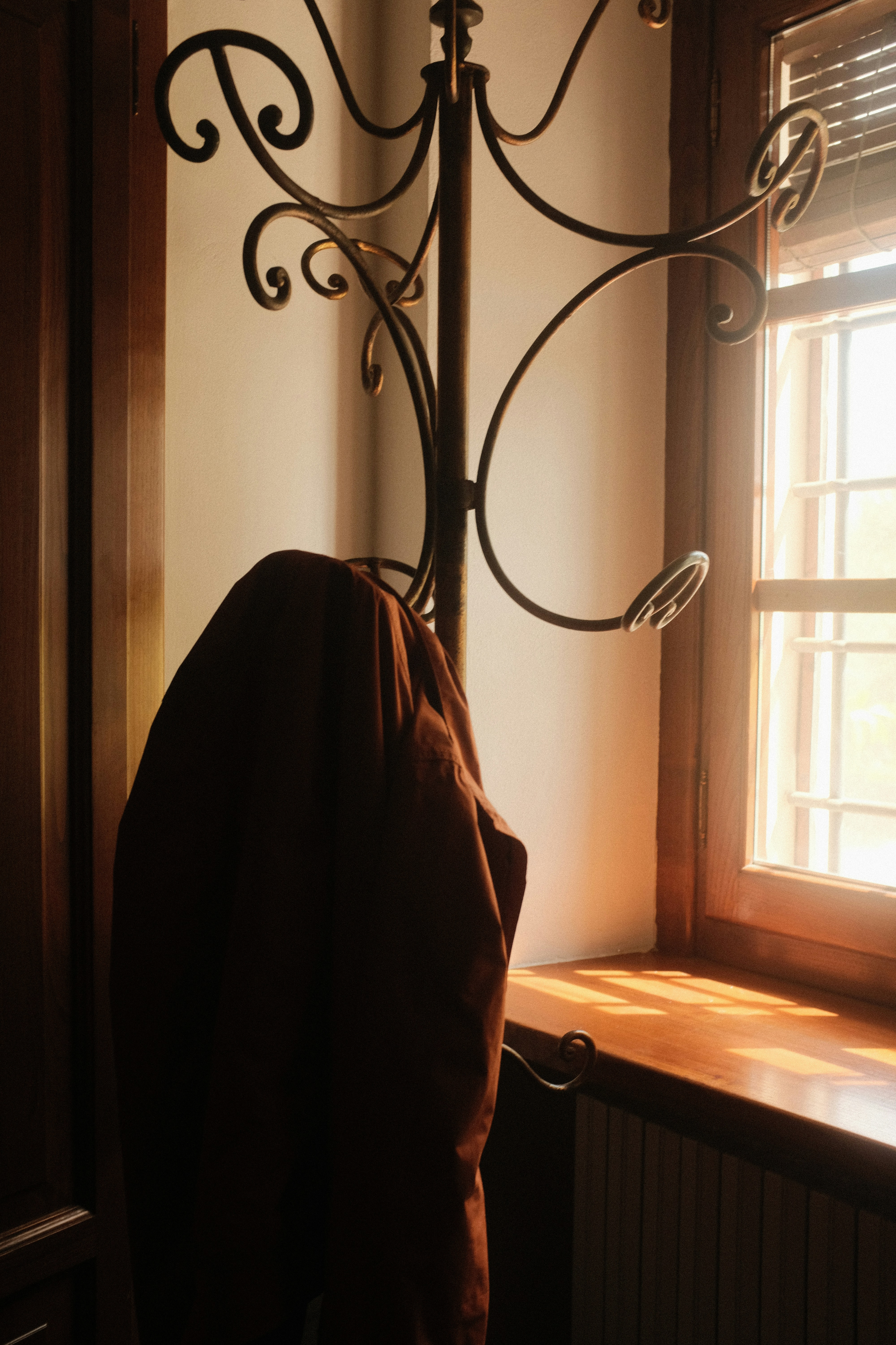A coat hanging on a coat rack next to a window