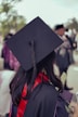 A woman in a graduation cap and gown looking at her cell phone