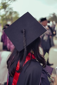 A woman in a graduation cap and gown looking at her cell phone