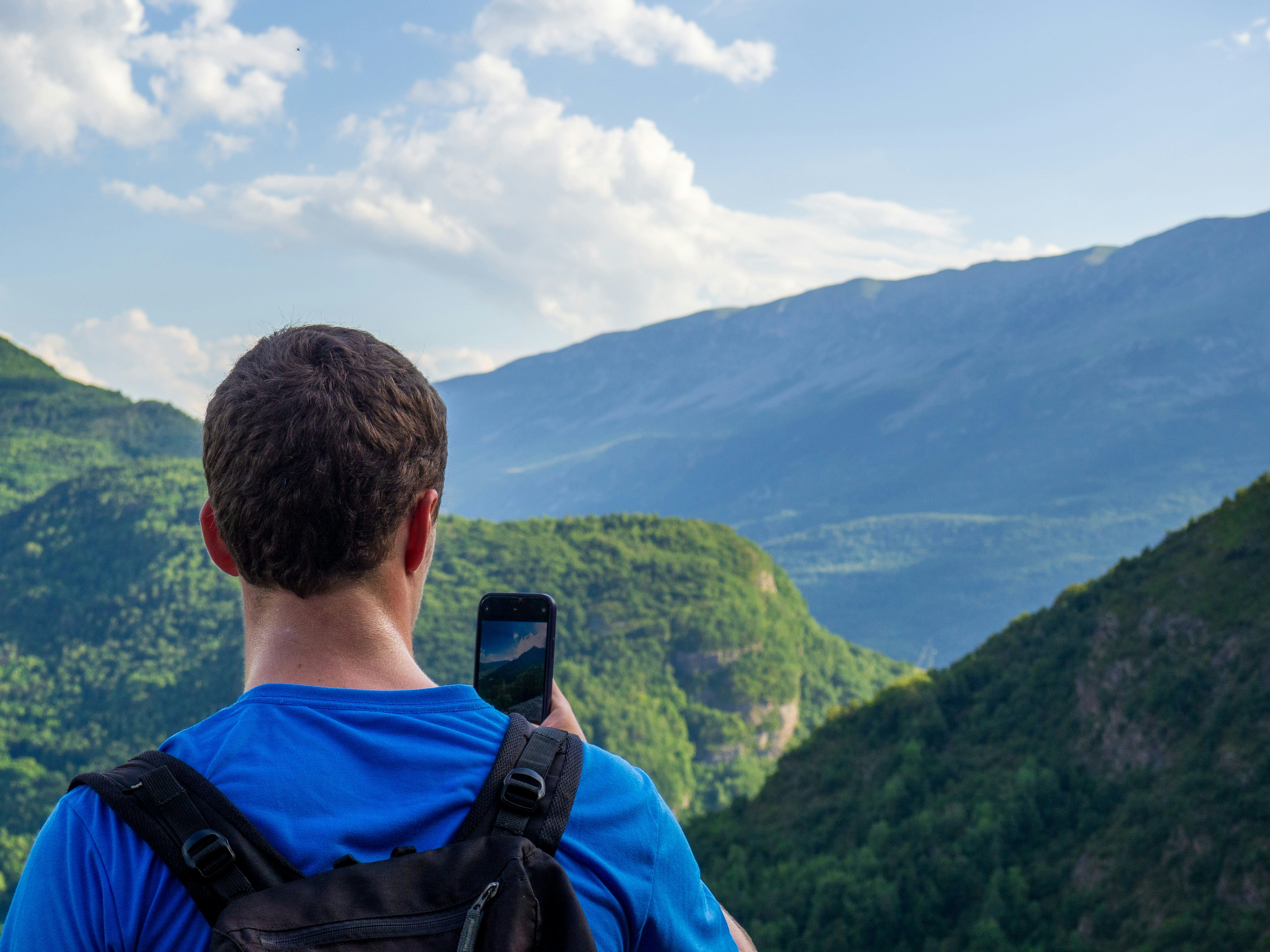 A man taking a picture of mountains with his cell phone