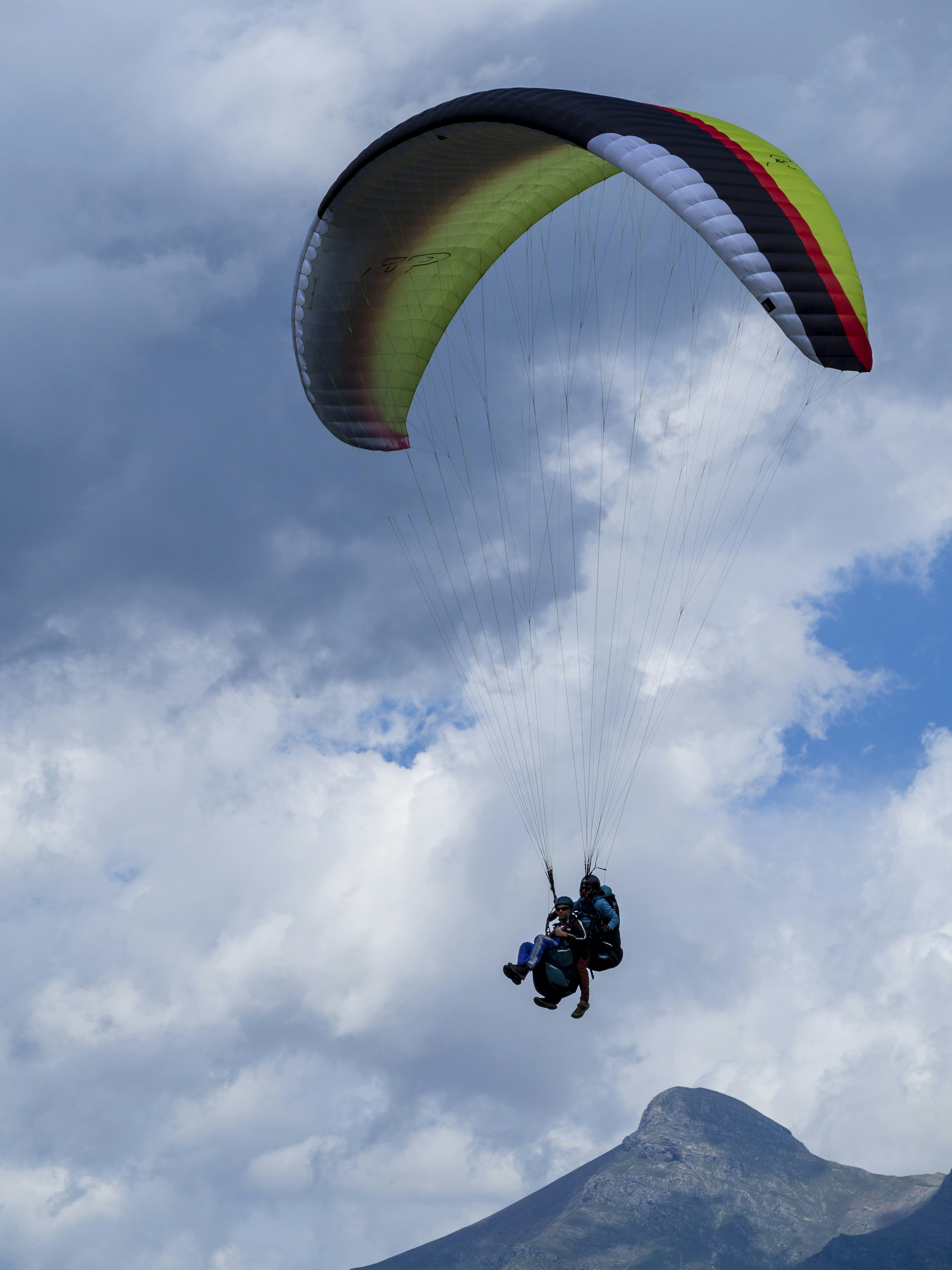 A person is parasailing in the sky with a mountain in the background