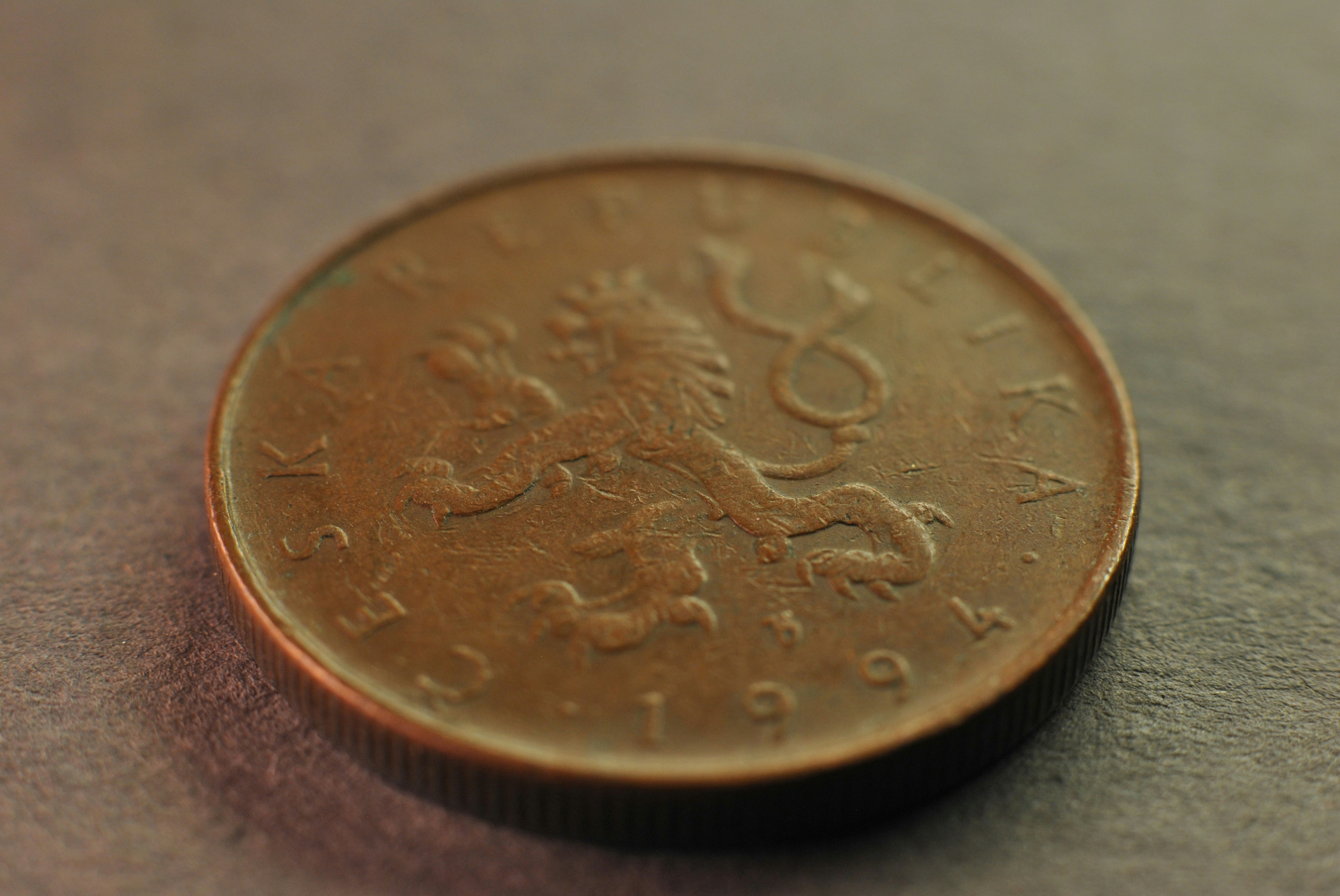 A person's hand carefully places a coin into a white, house-shaped piggy bank, symbolizing saving money and protecting home equity.