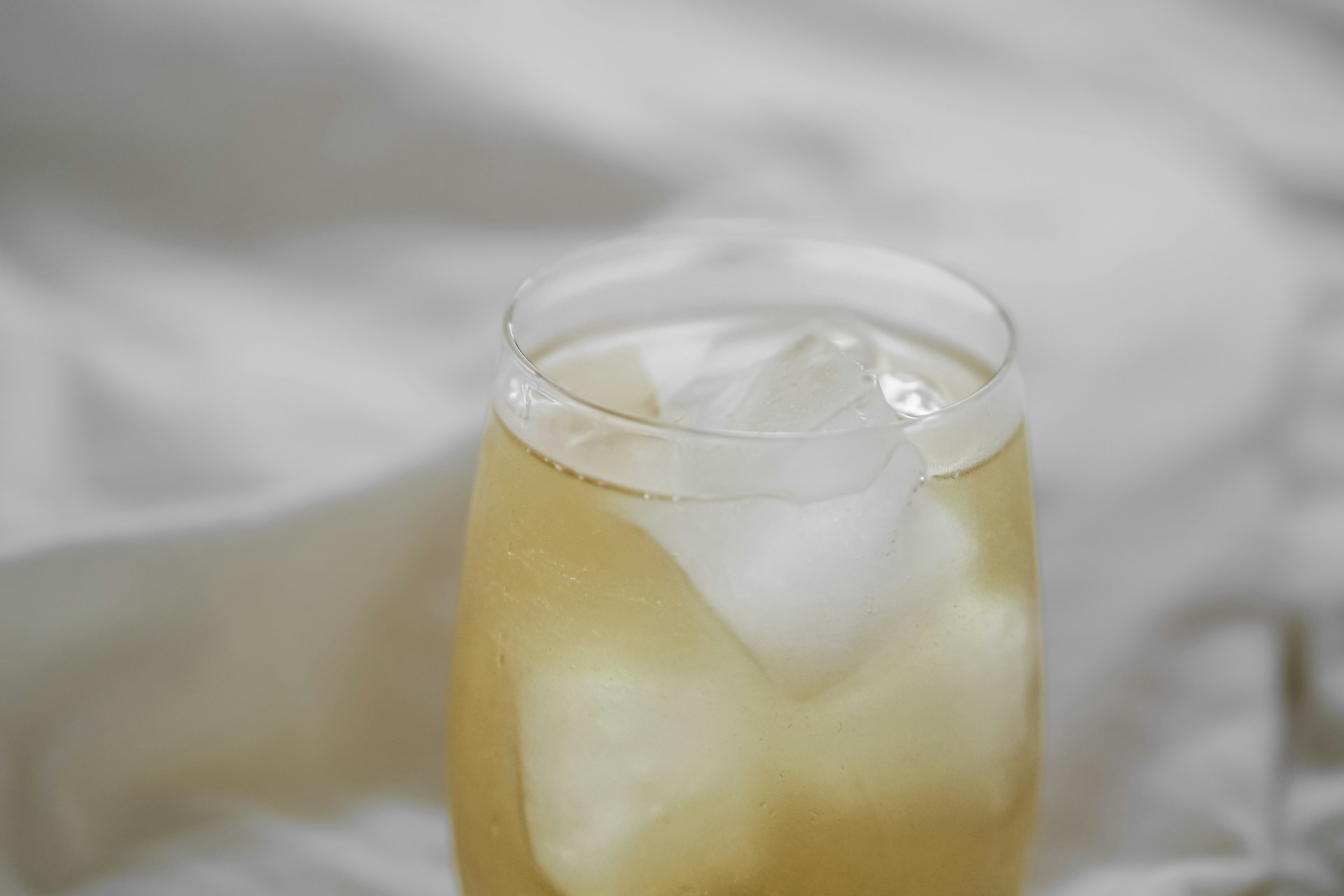 A glass of lemonade sitting on top of a bed
