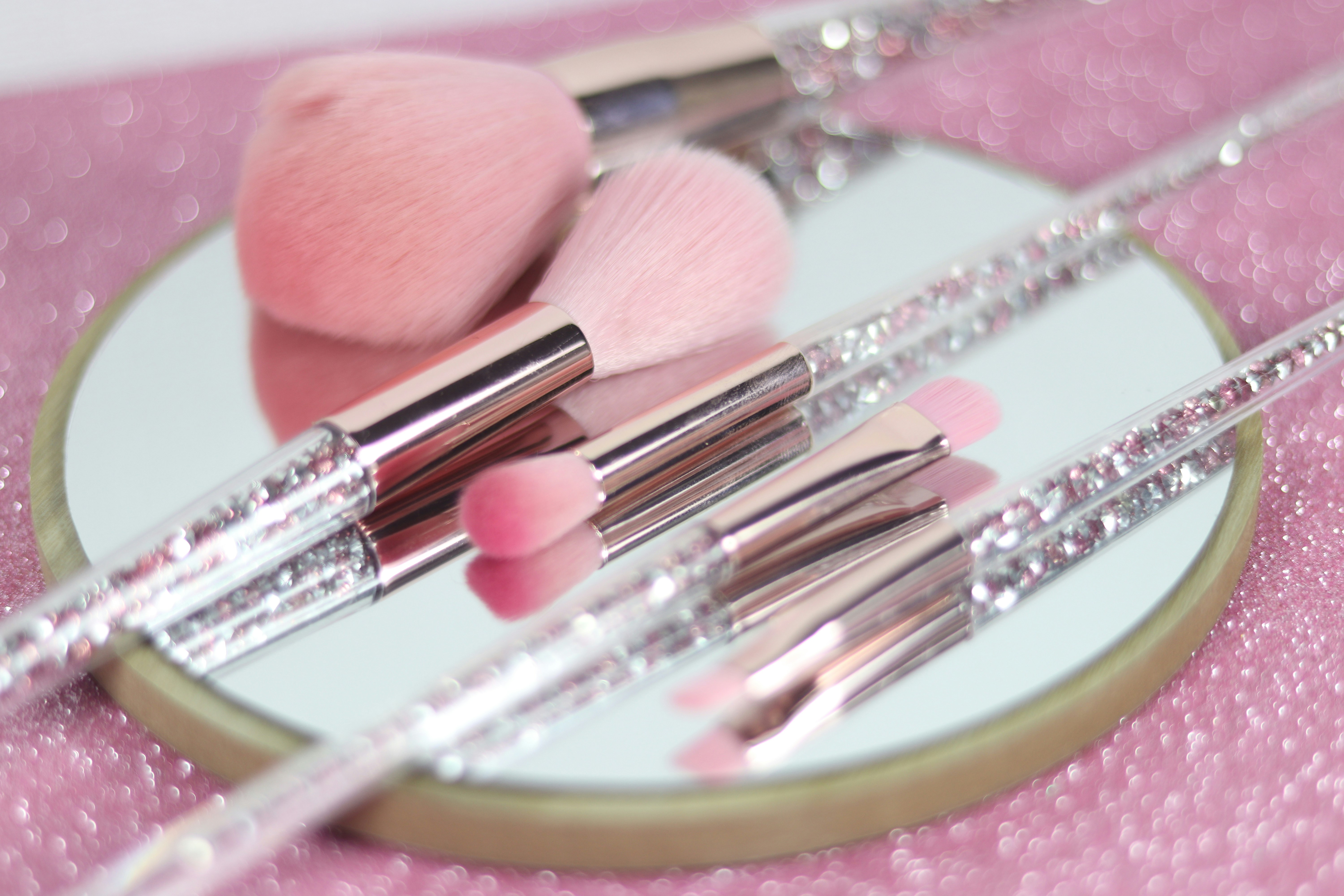 Pink makeup brushes reflected in a mirror