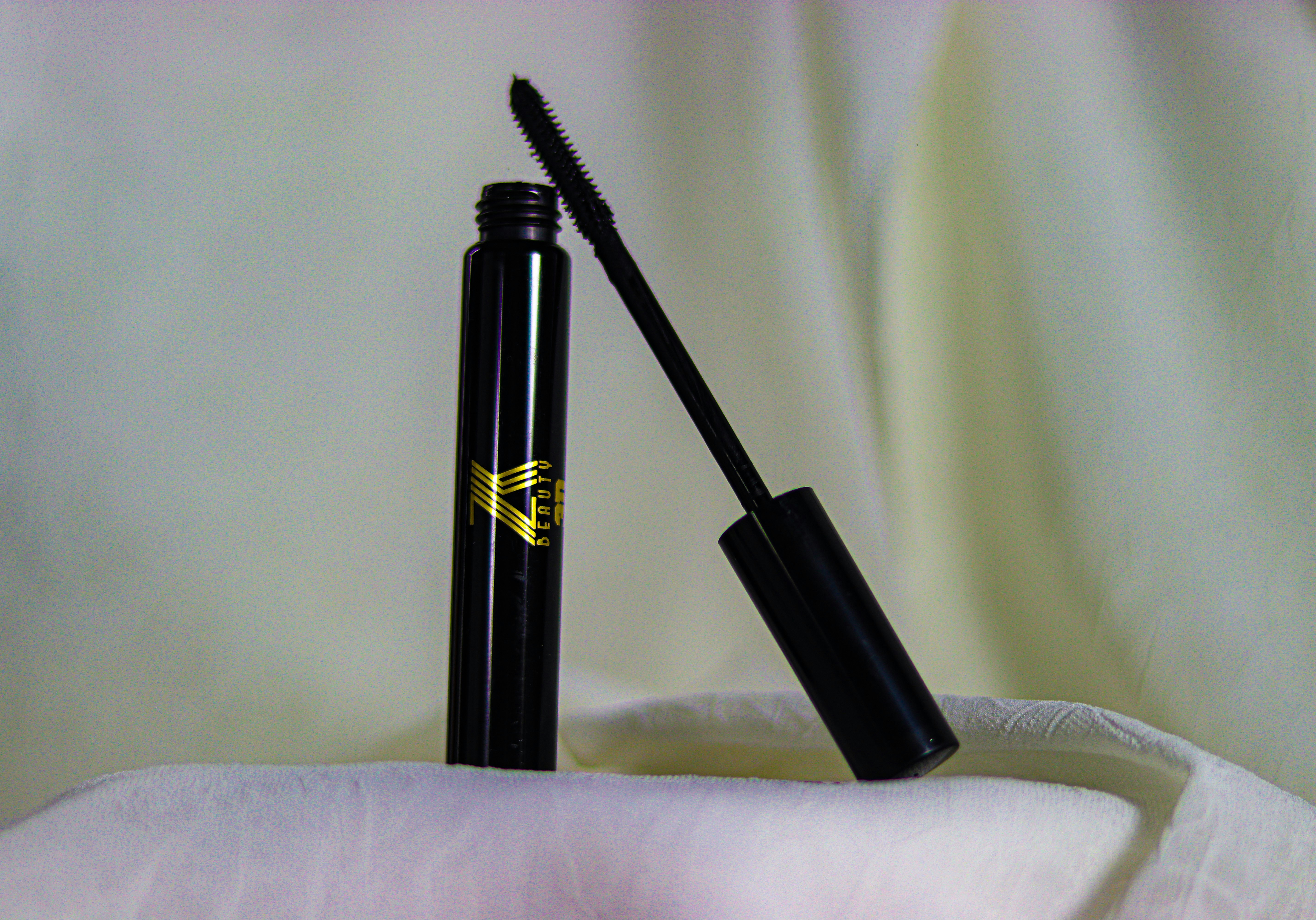 Mascara wand and tube on dark elegant background, luxury eye makeup product