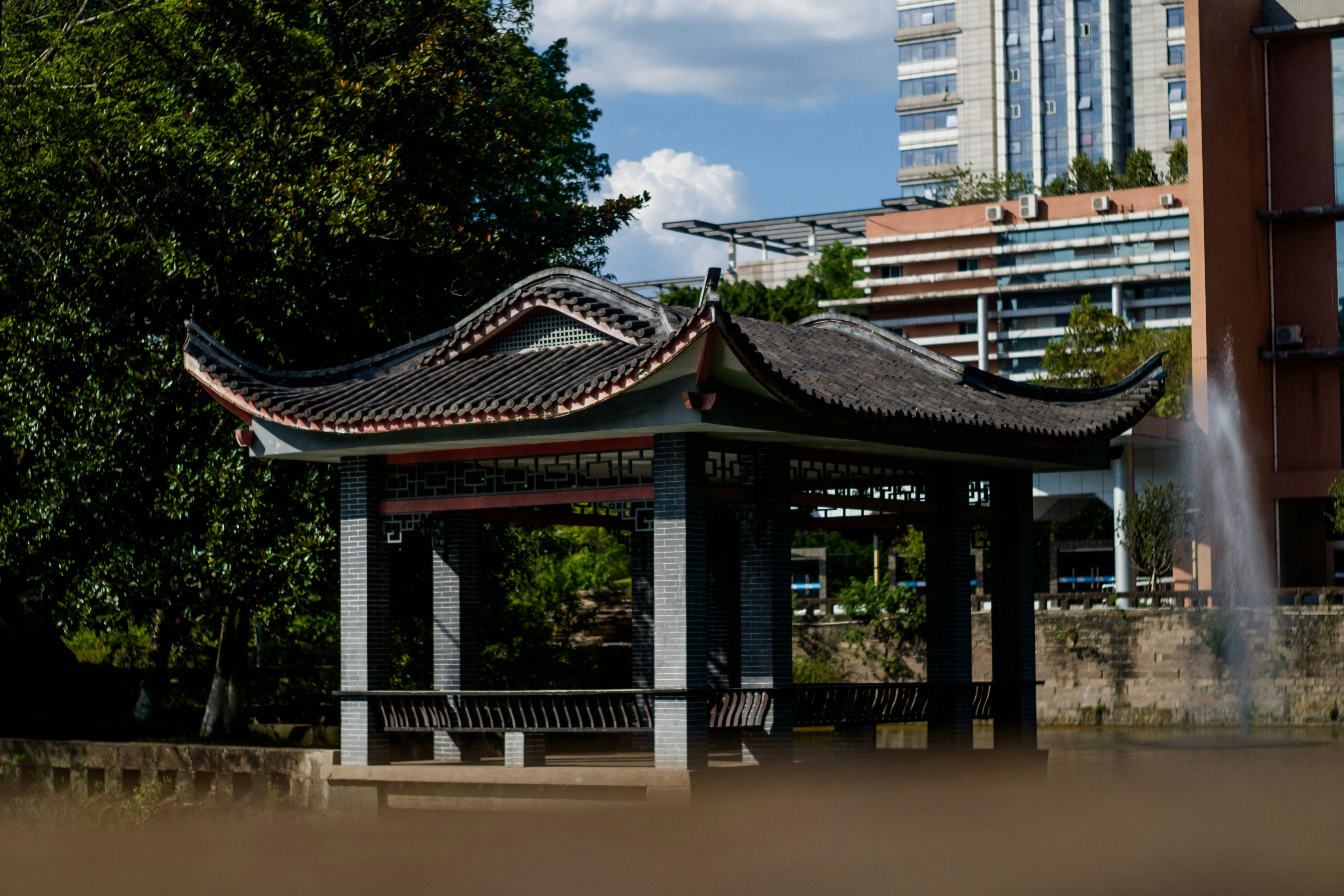 A gazebo in the middle of a park with buildings in the background