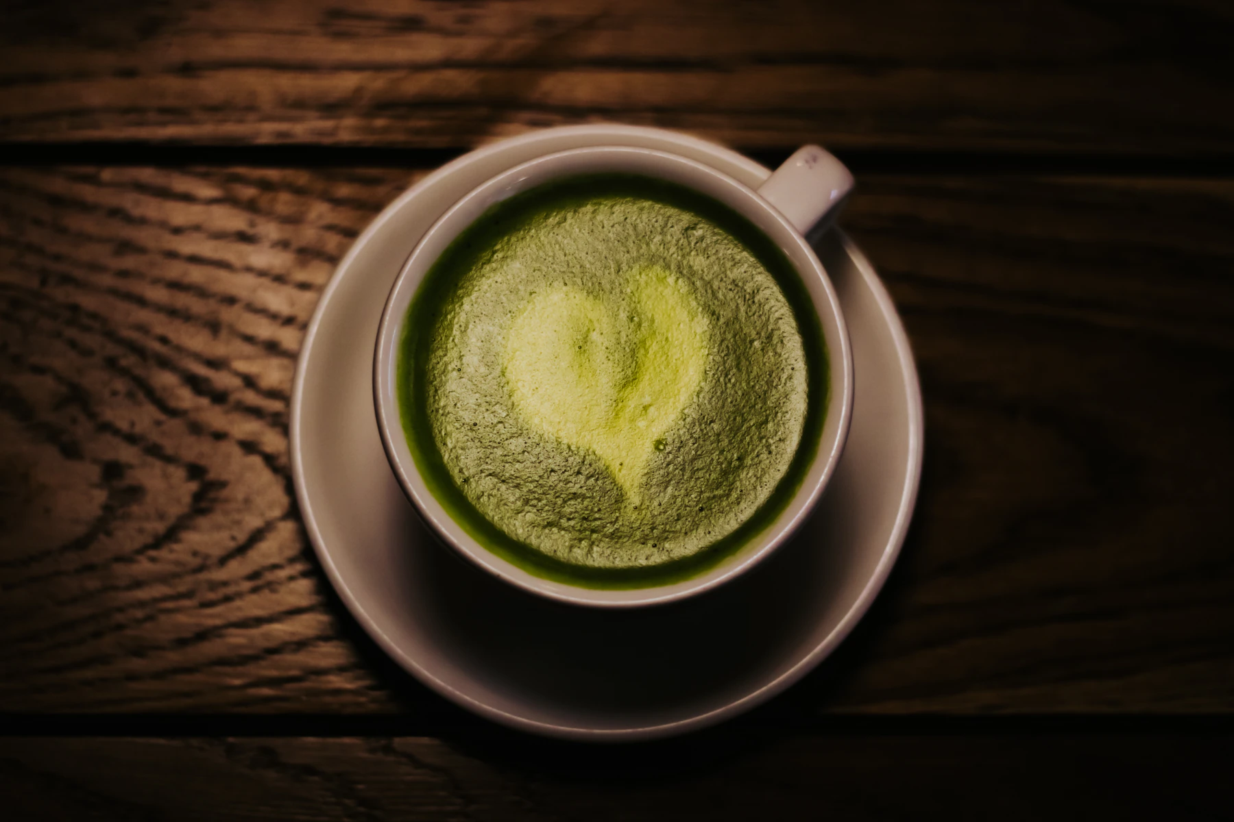 Green matcha served in a ceramic cup on a wooden table