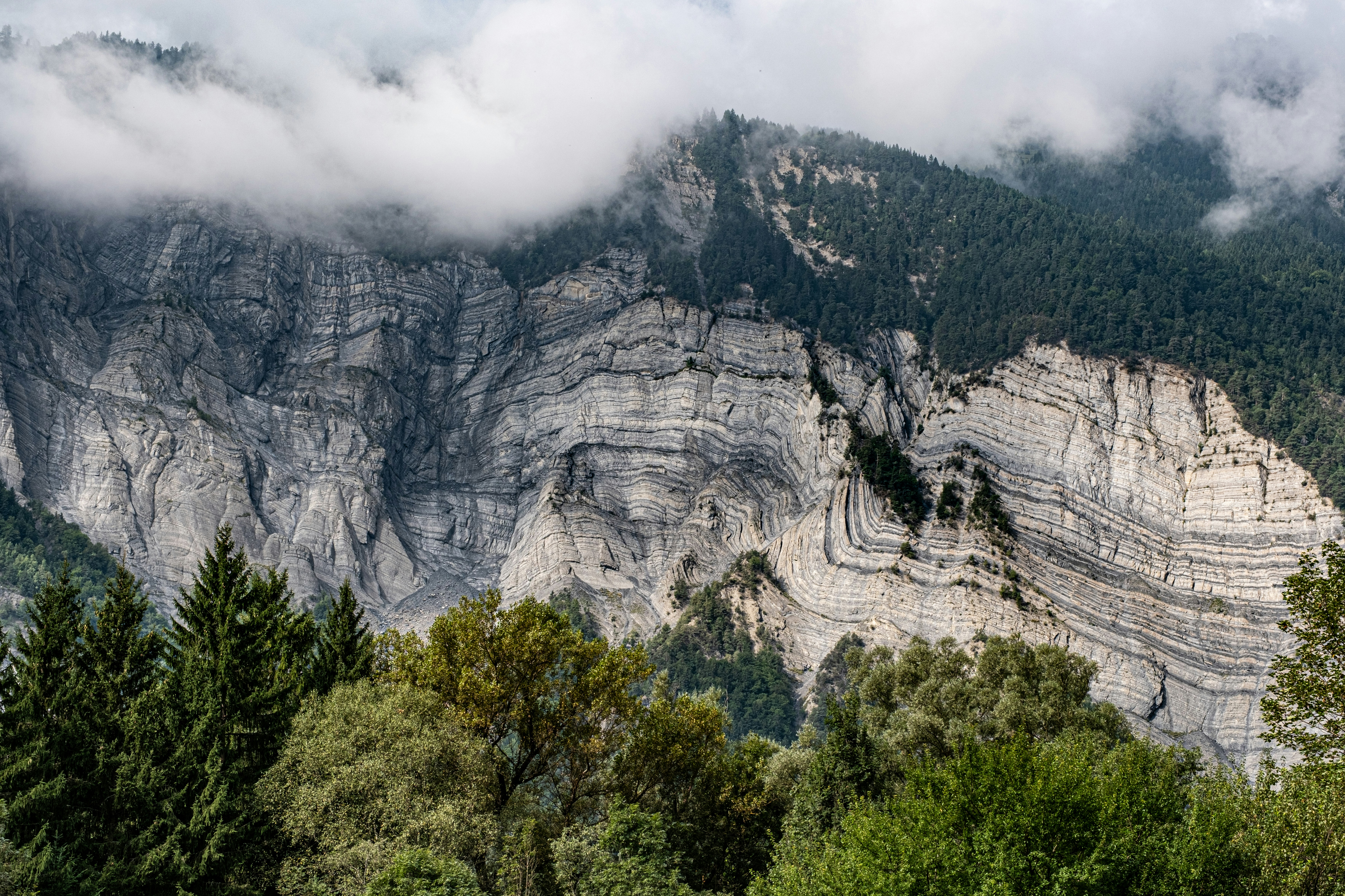 A view of a mountain range with trees and clouds