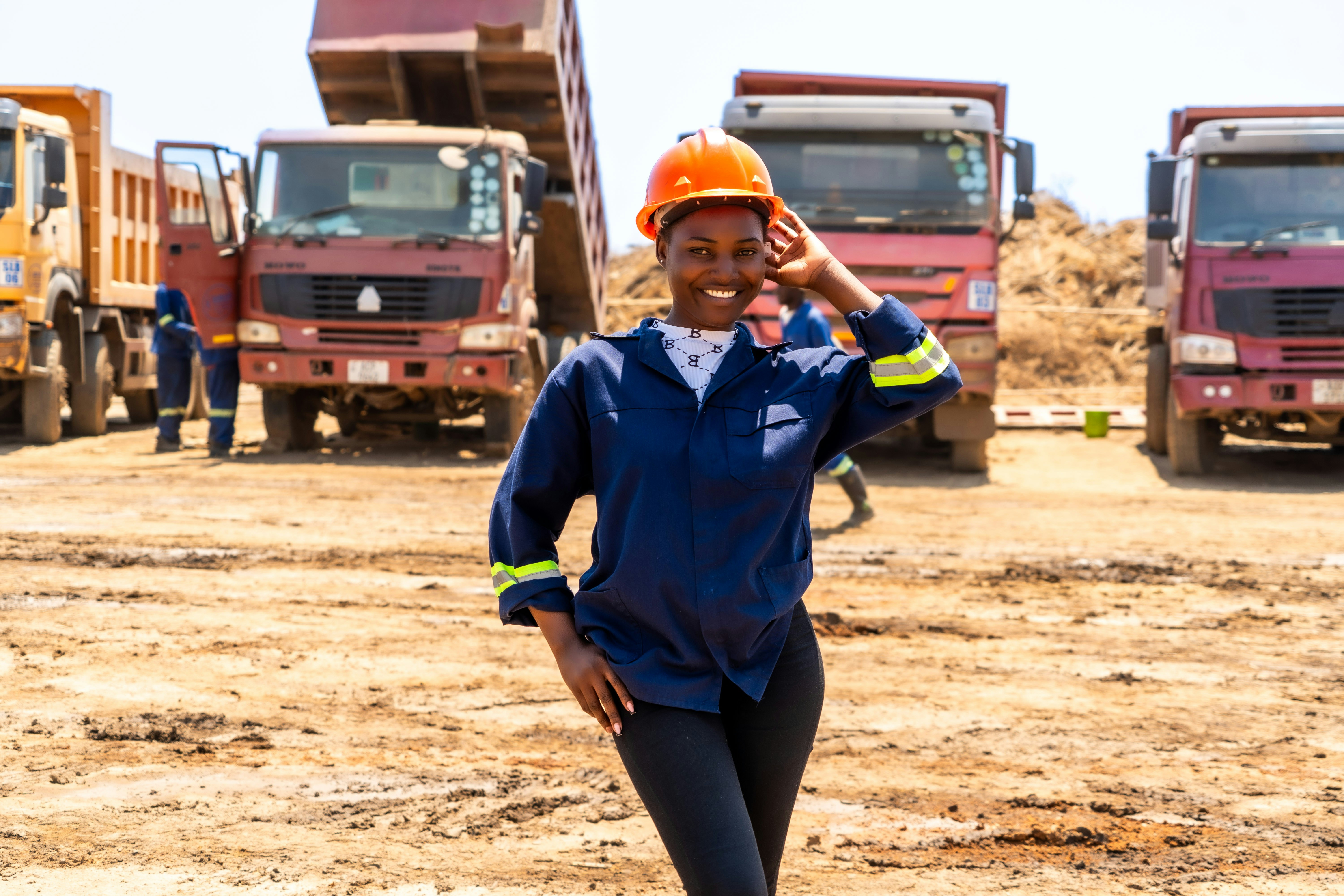 A woman standing in a dirt field next to trucks