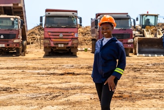 A woman standing in a dirt field next to trucks