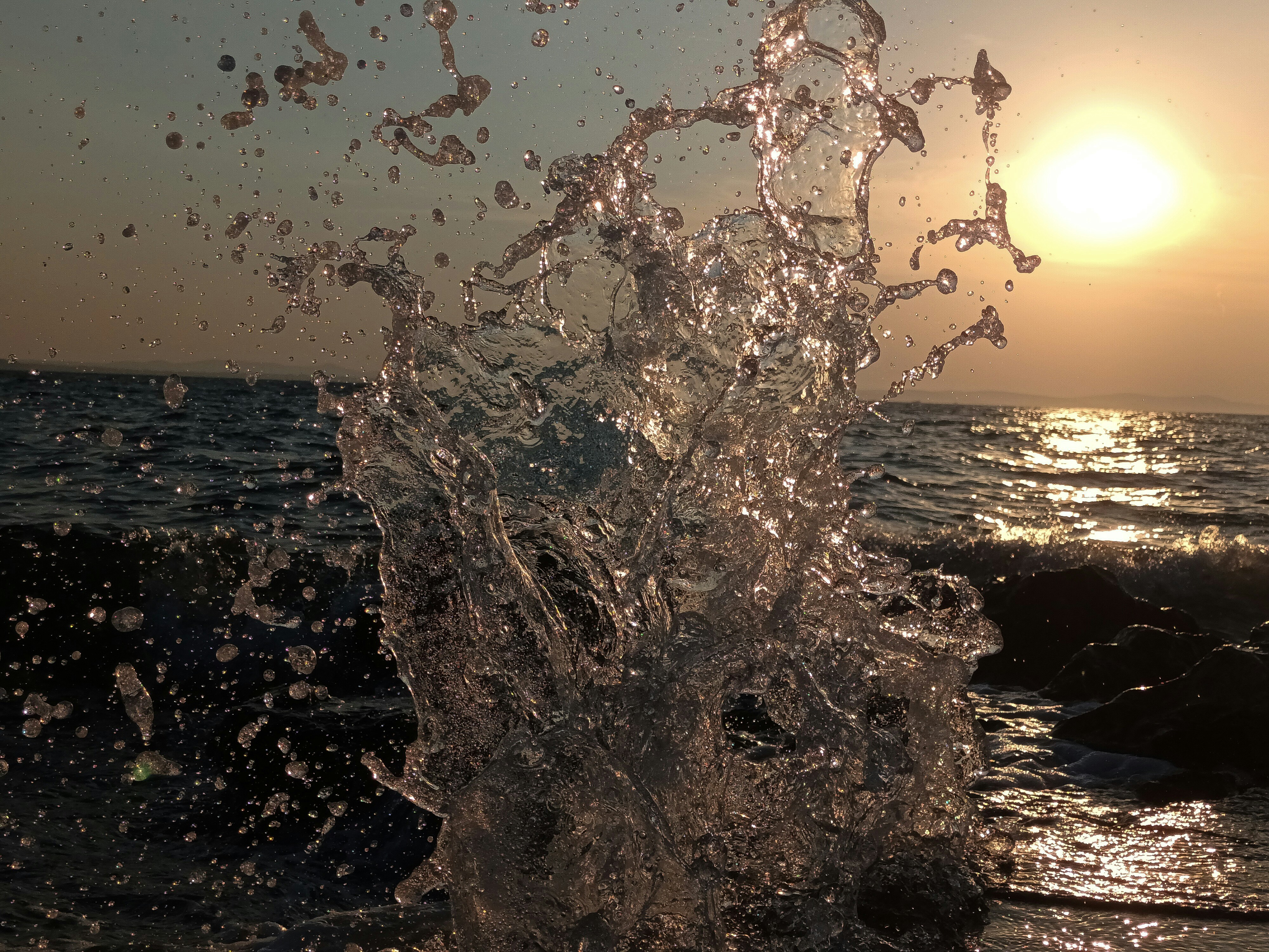 A splash of water on a beach at sunset