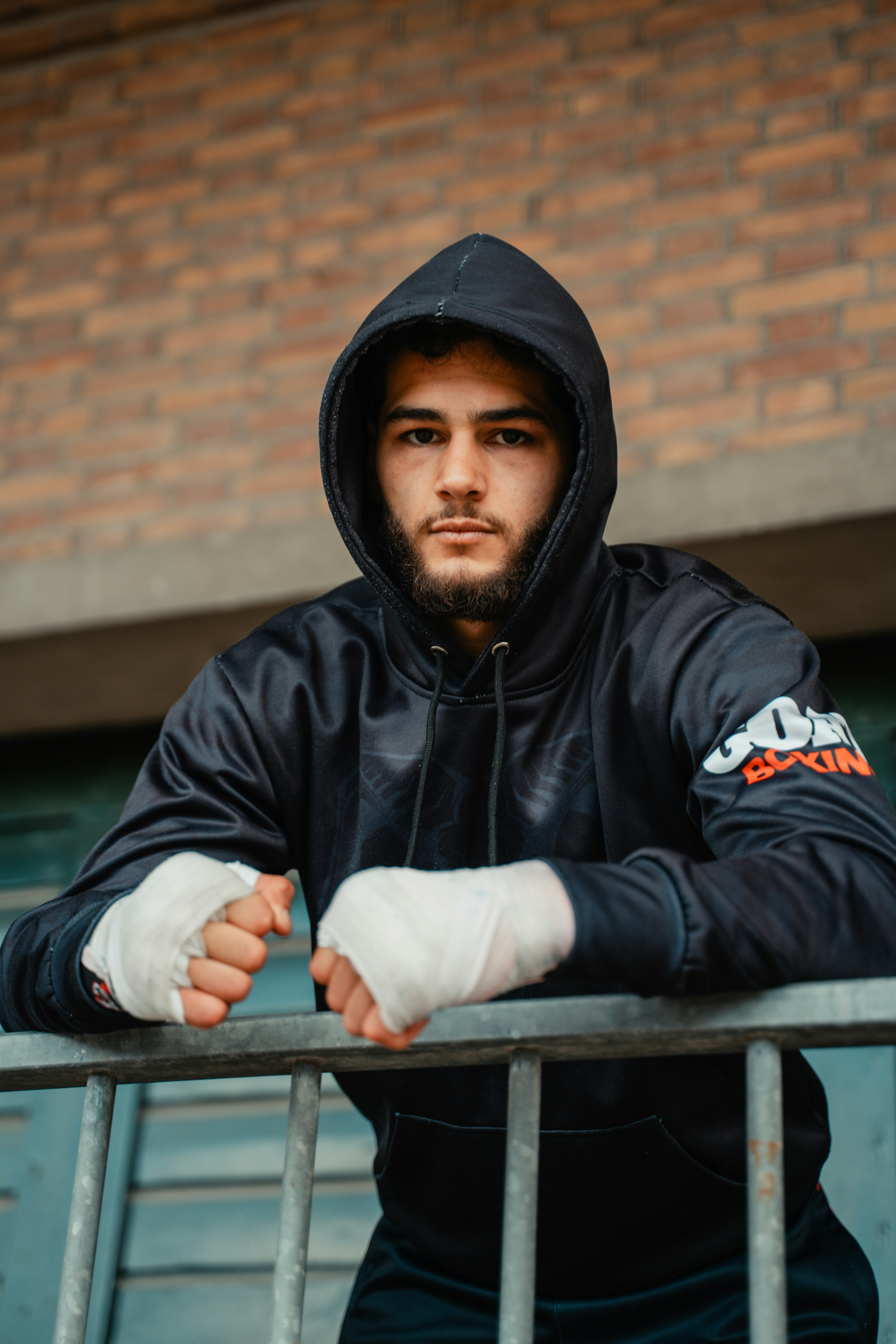 A man in a black hoodie with a bandage on his arm