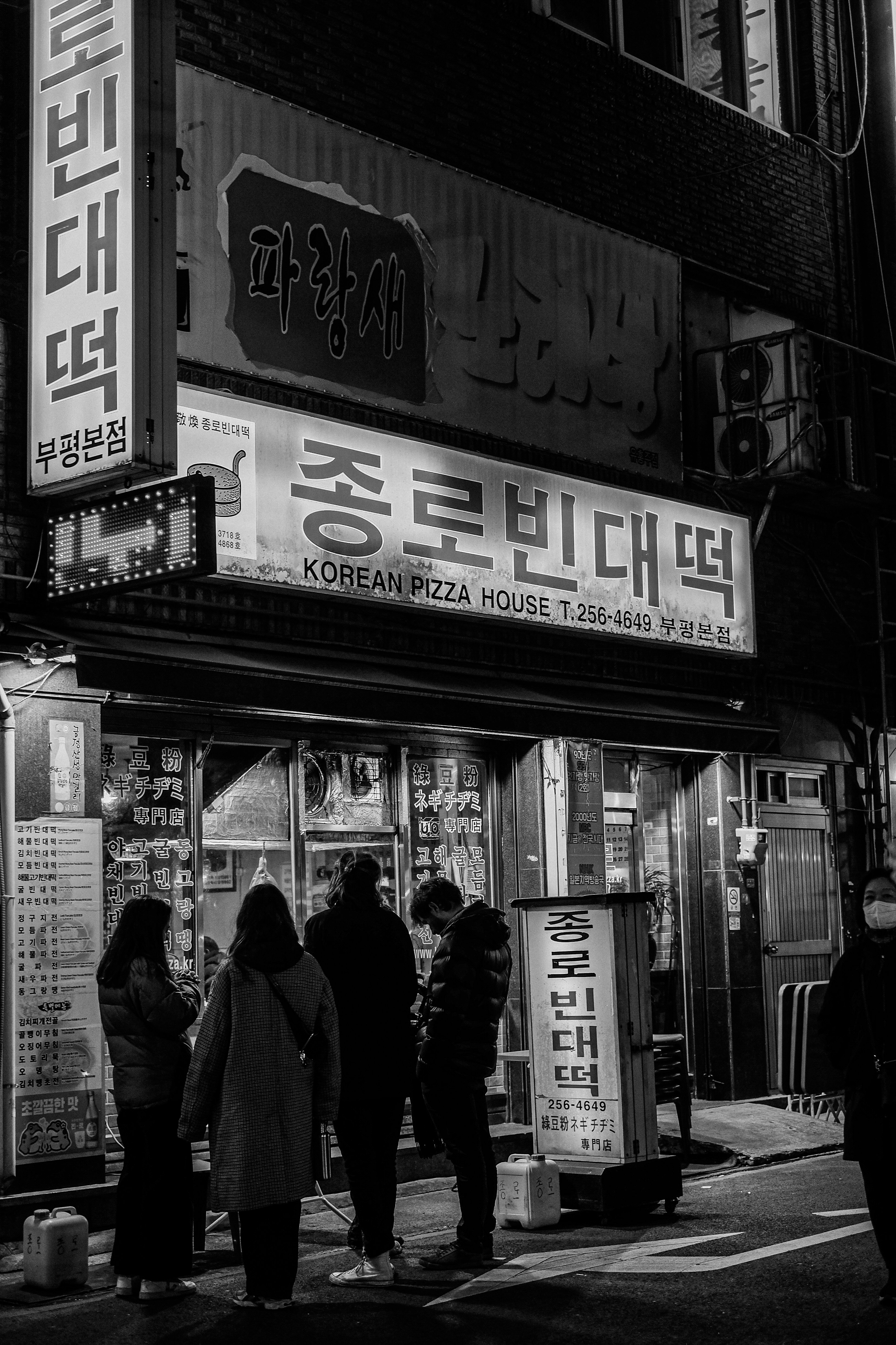 A group of people standing outside of a store at night