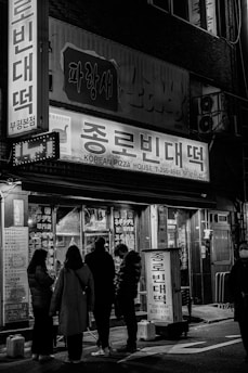 A group of people standing outside of a store at night