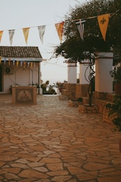 A cobblestone patio with flags and potted plants