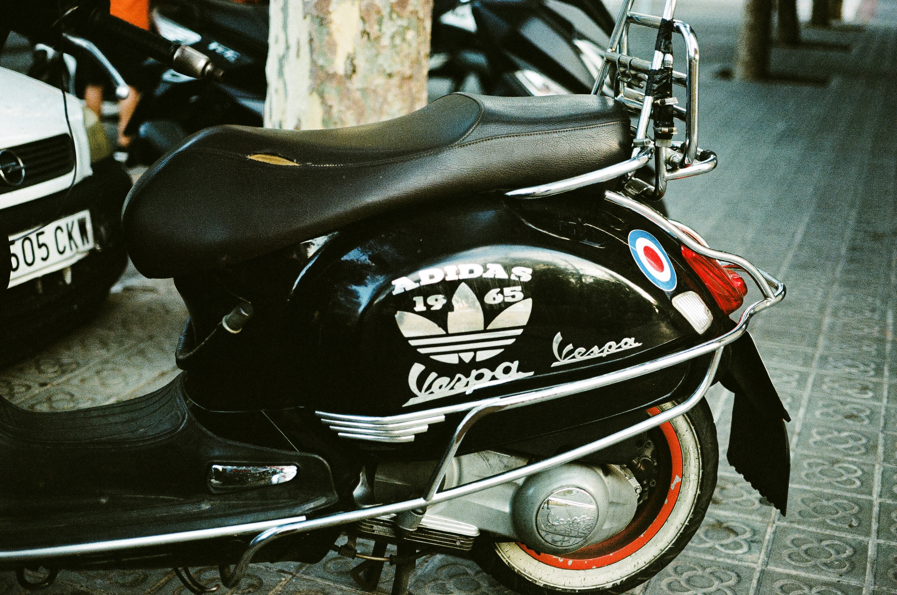 A motor scooter parked next to a tree
