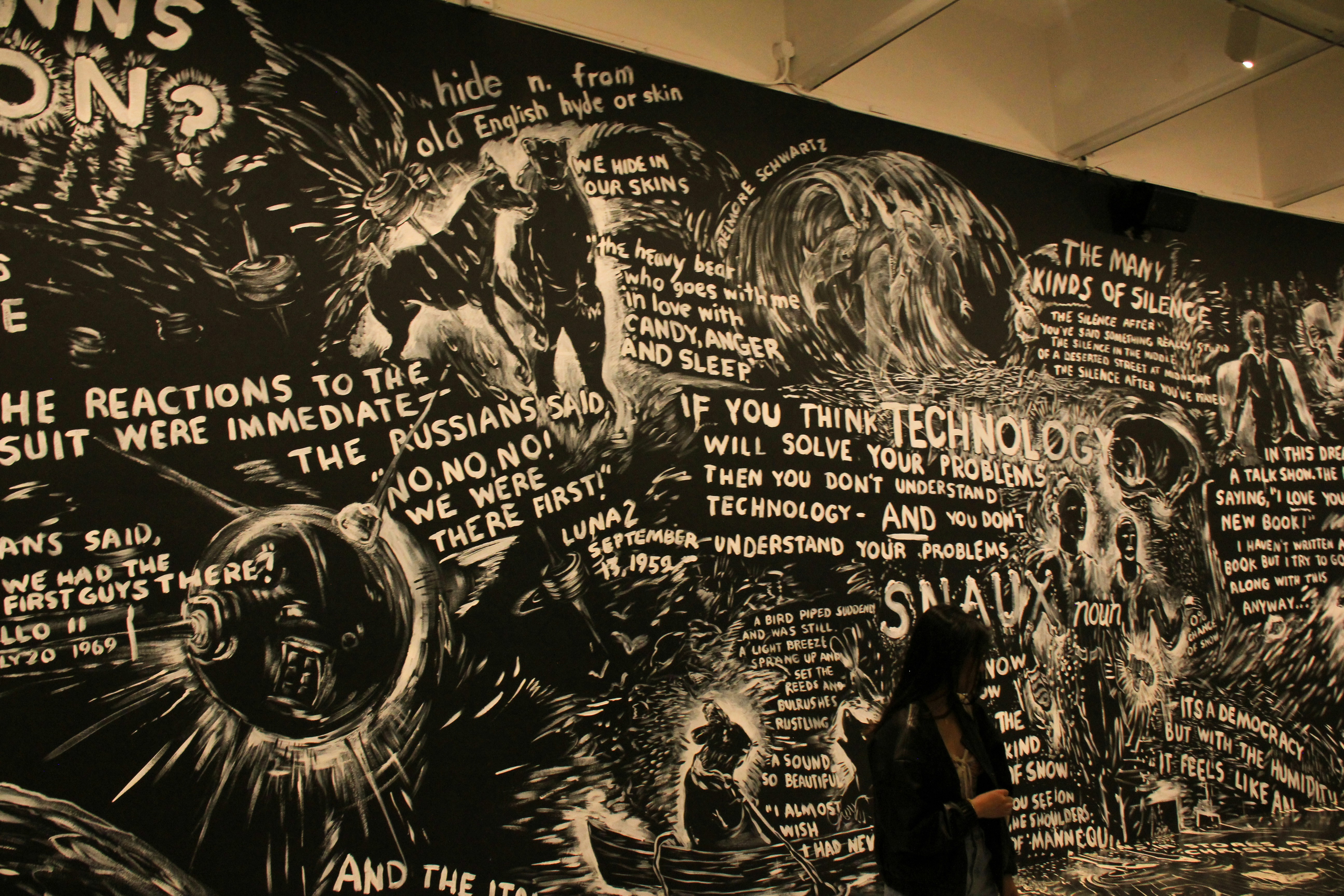 Una mujer de pie frente a un mural en blanco y negro