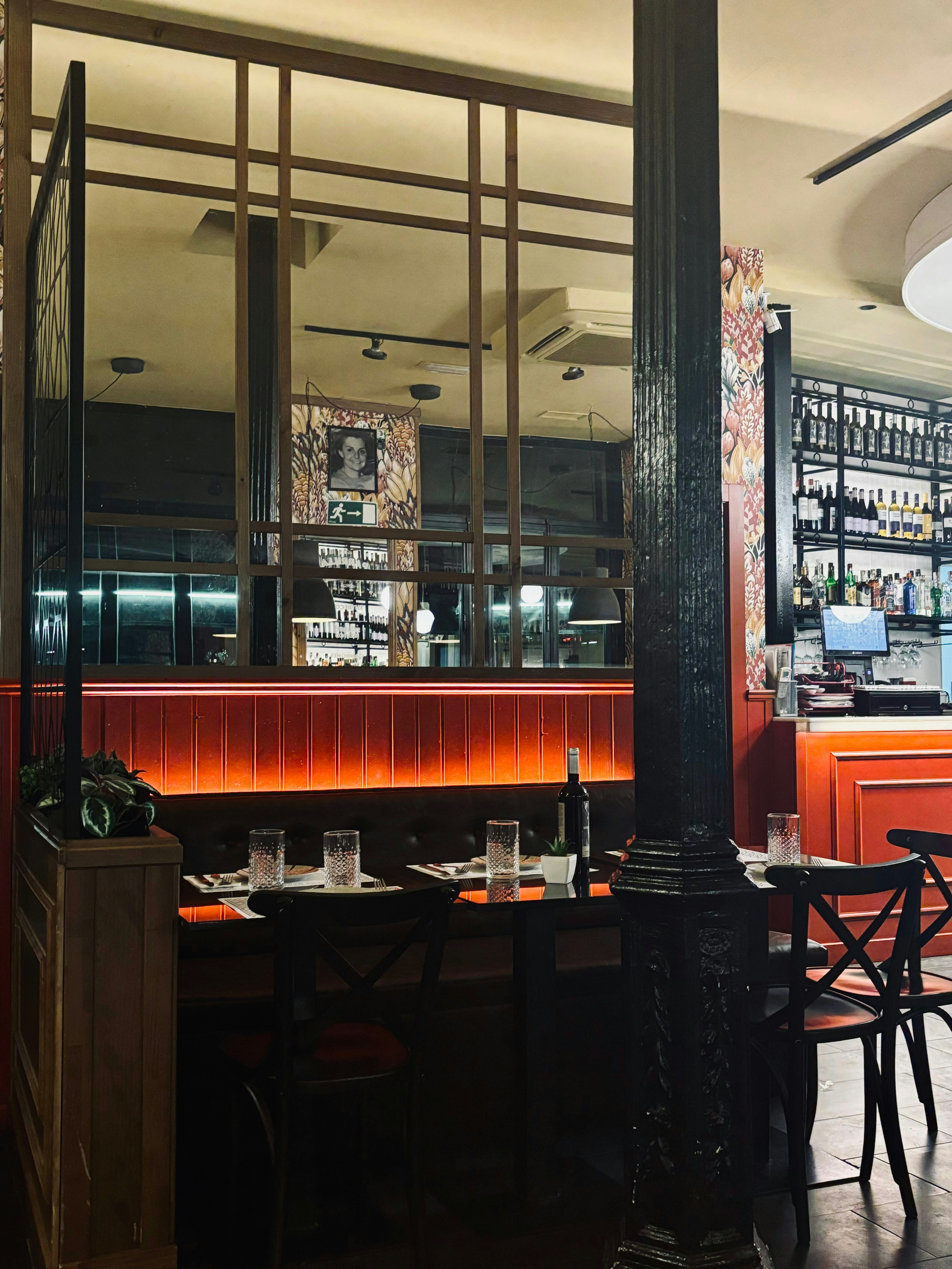 Professional wine service with elegant wine glasses and fresh grapes on wooden table in warm restaurant lighting