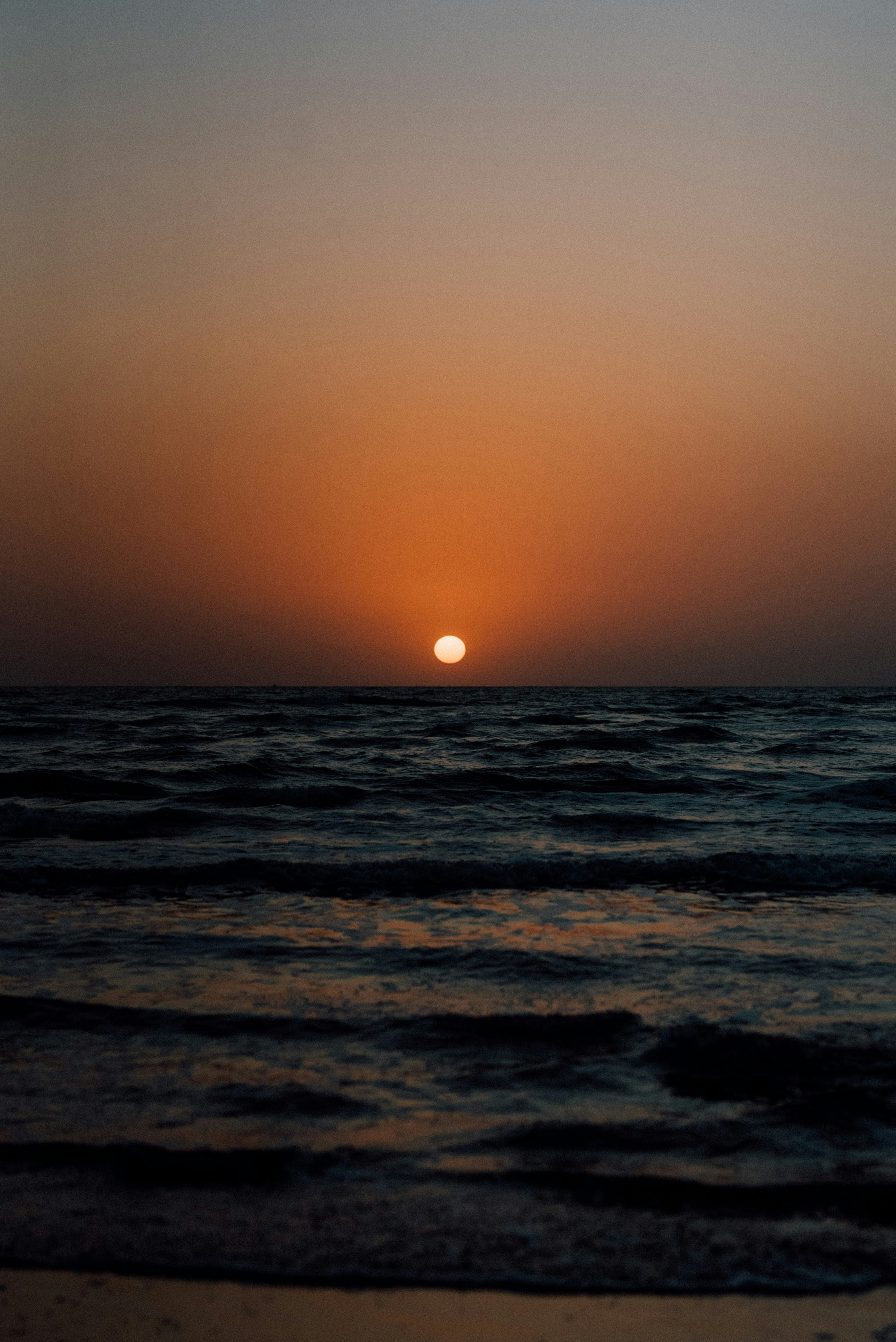 해변의 바다 위로 해가 지고 있습니다