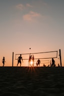 A group of people playing volleyball on a beach