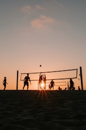 A group of people playing volleyball on a beach