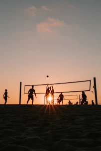 A group of people playing volleyball on a beach