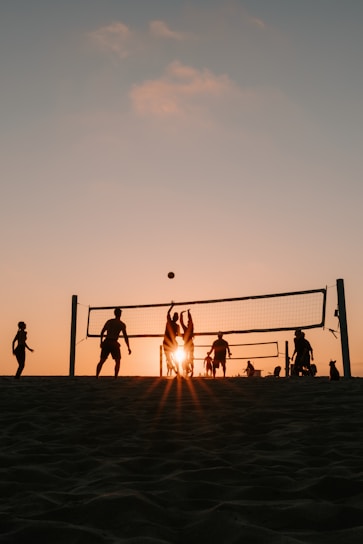 A group of people playing volleyball on a beach
