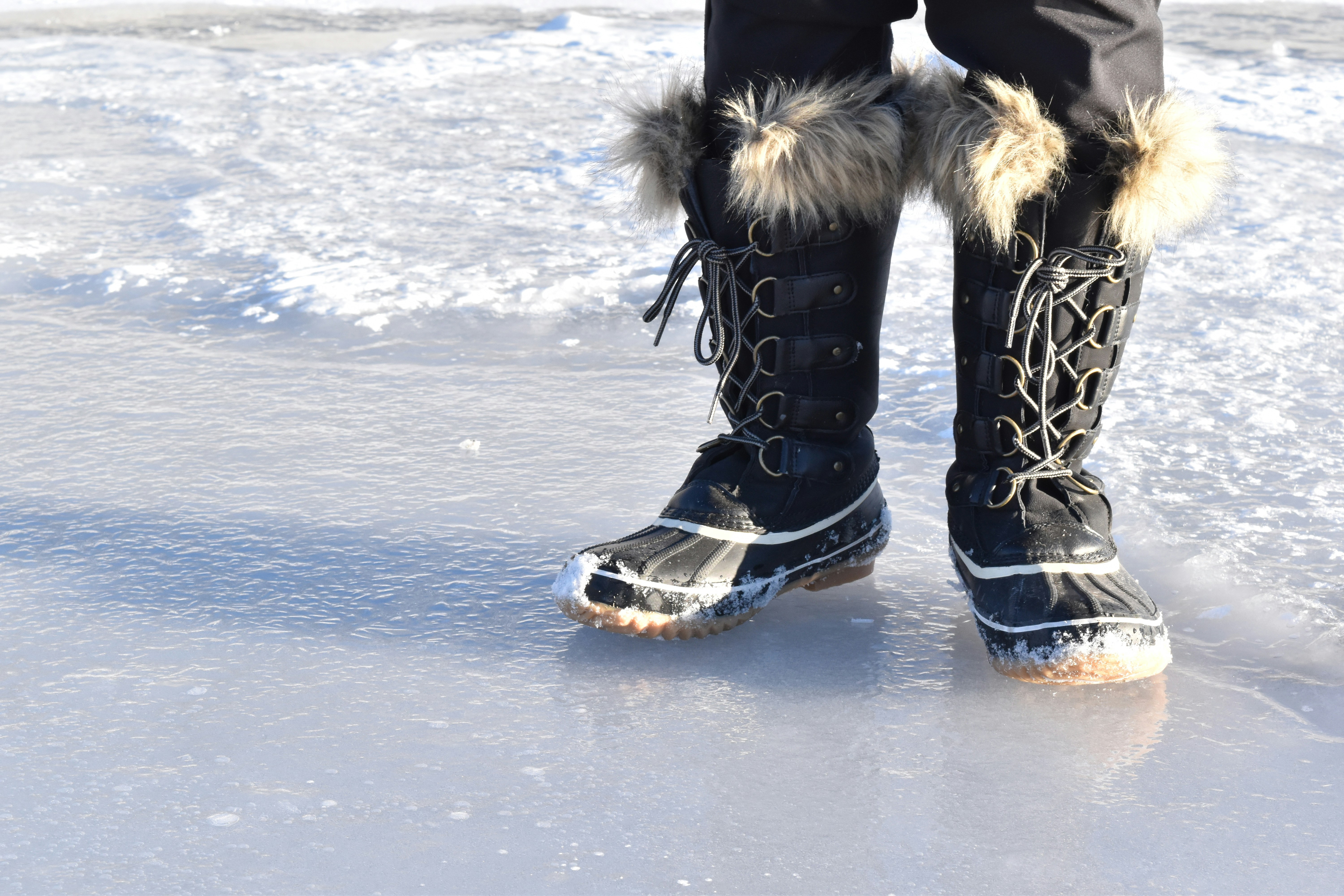 A person standing in the snow wearing boots