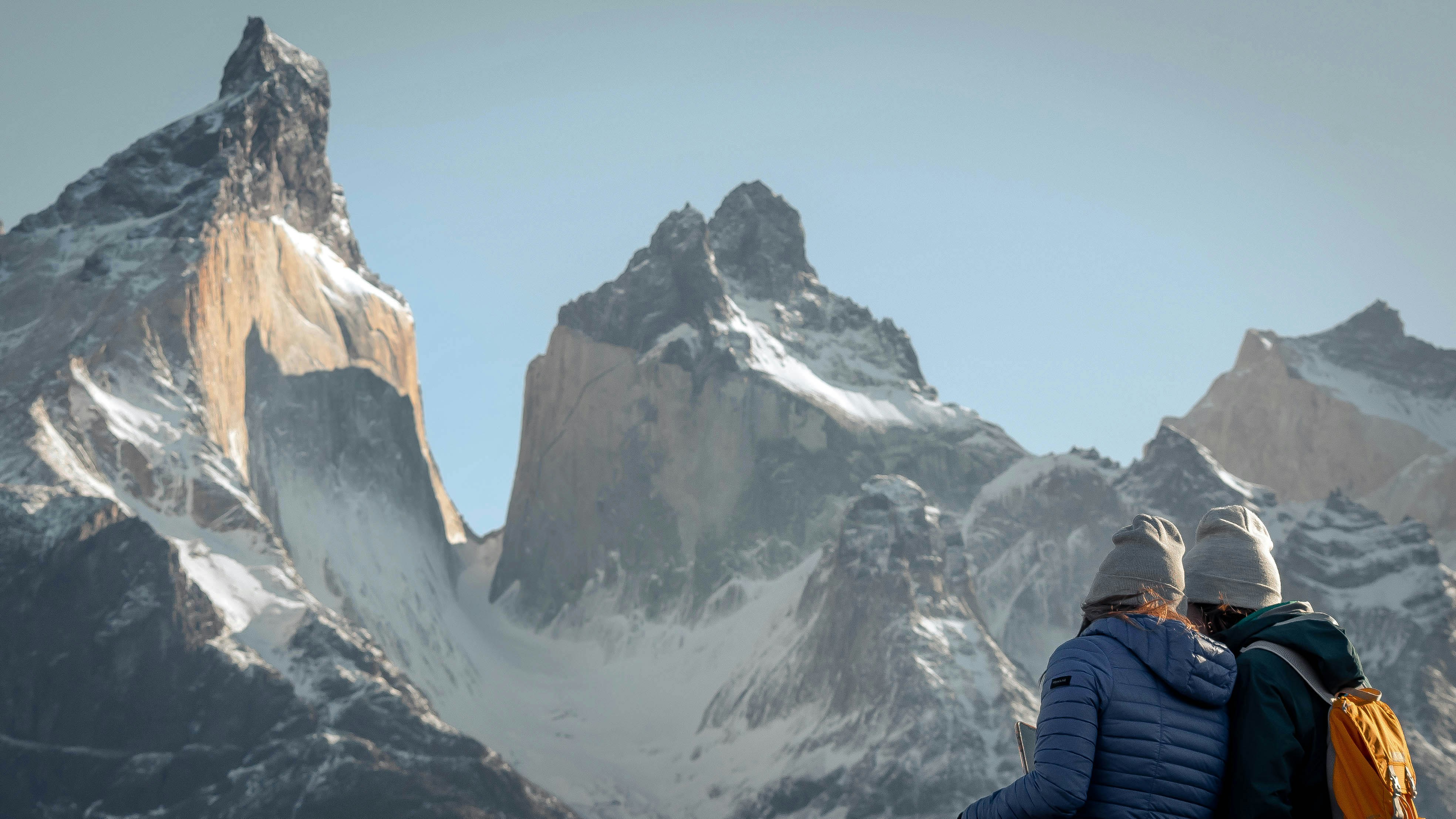 A couple of people standing on top of a snow covered mountain