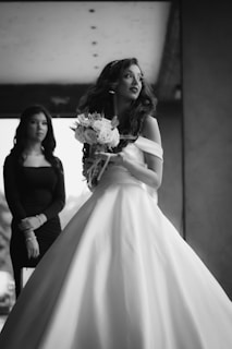A woman in a wedding dress standing next to another woman