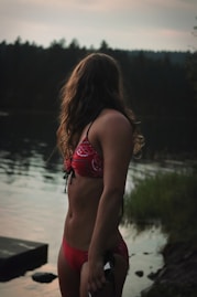 A woman in a red bikini standing next to a body of water