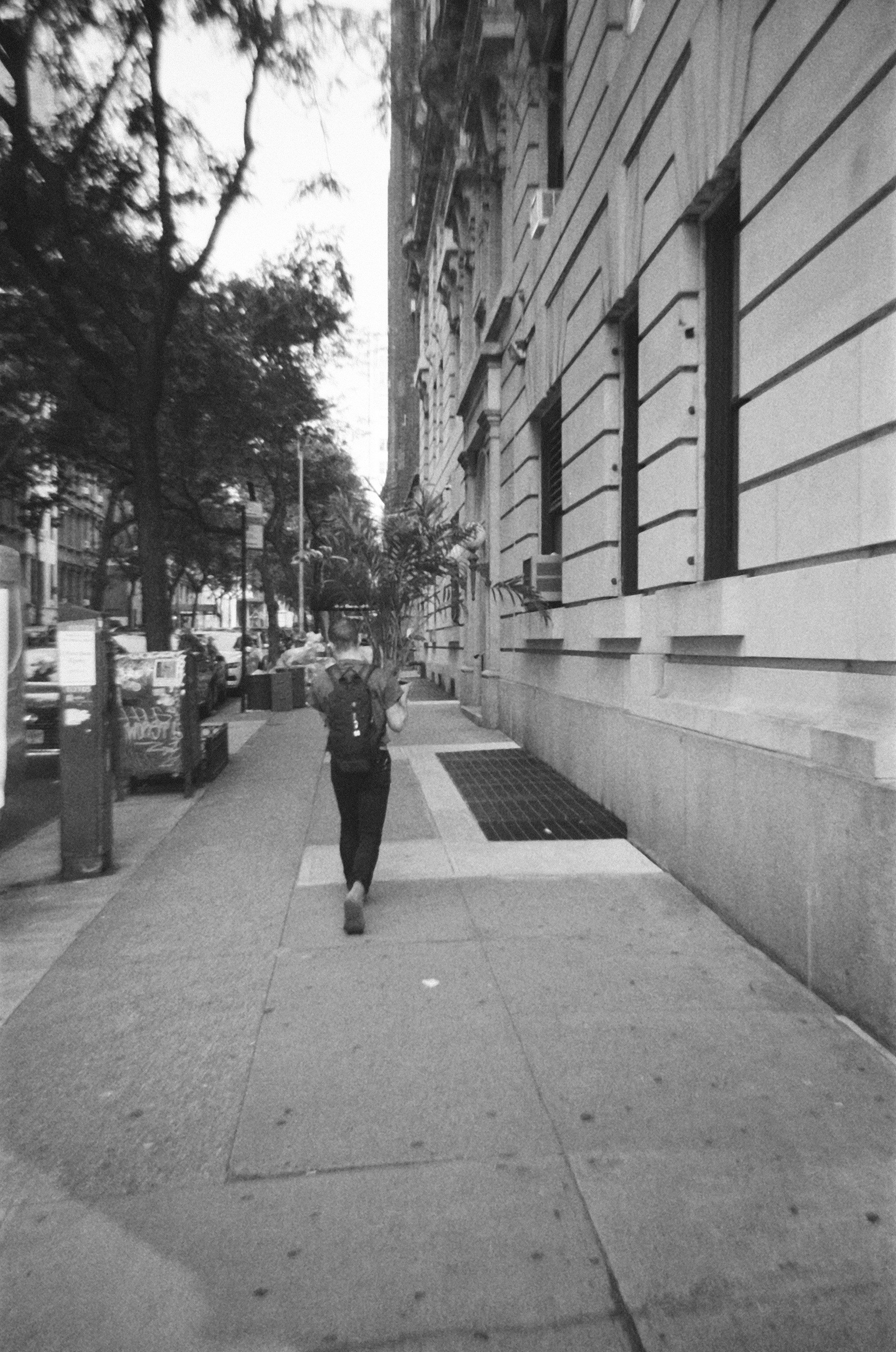A black and white photo of a person walking down a sidewalk
