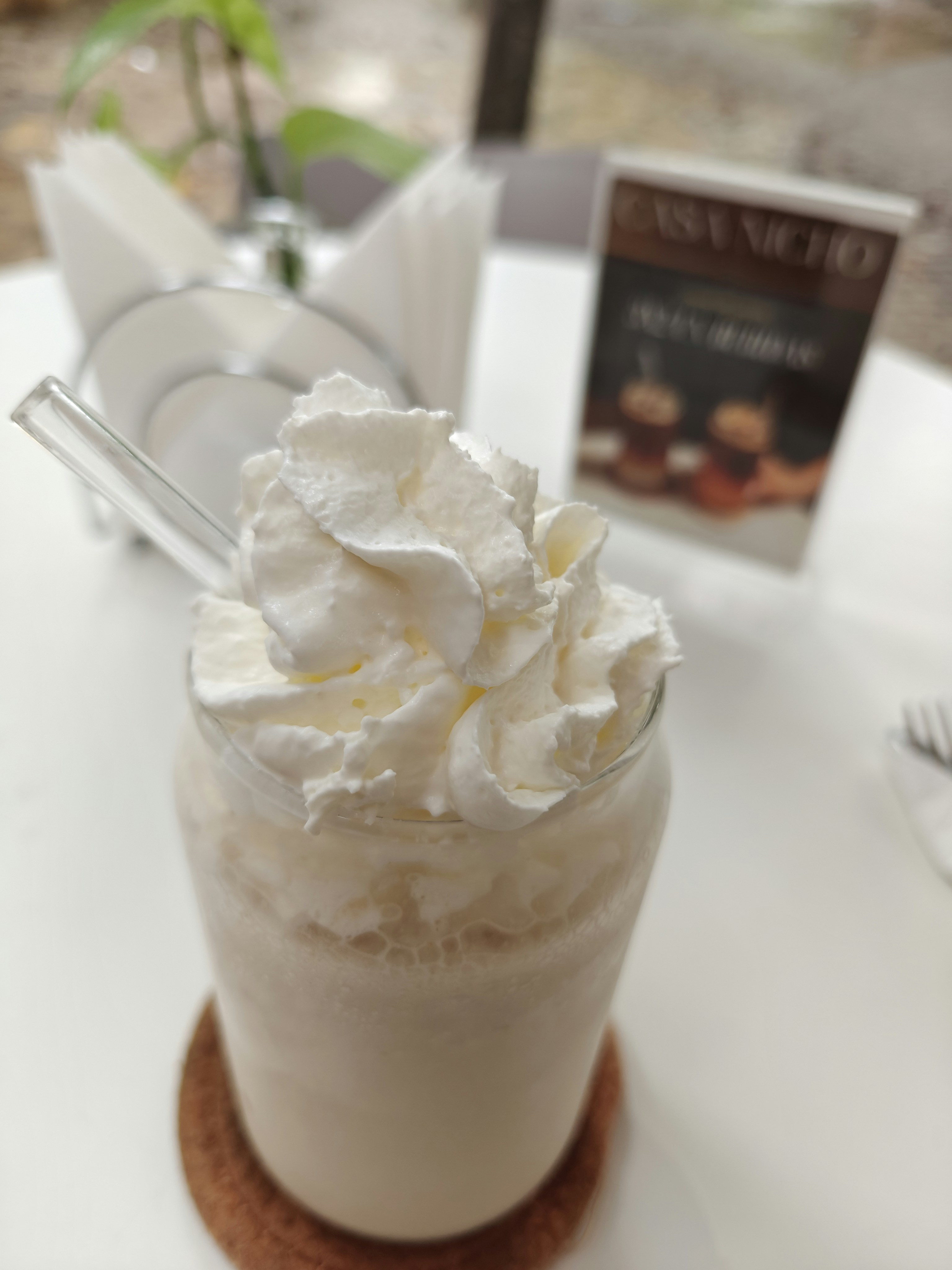 Thick creamy milkshake with whipped cream and straw in glass