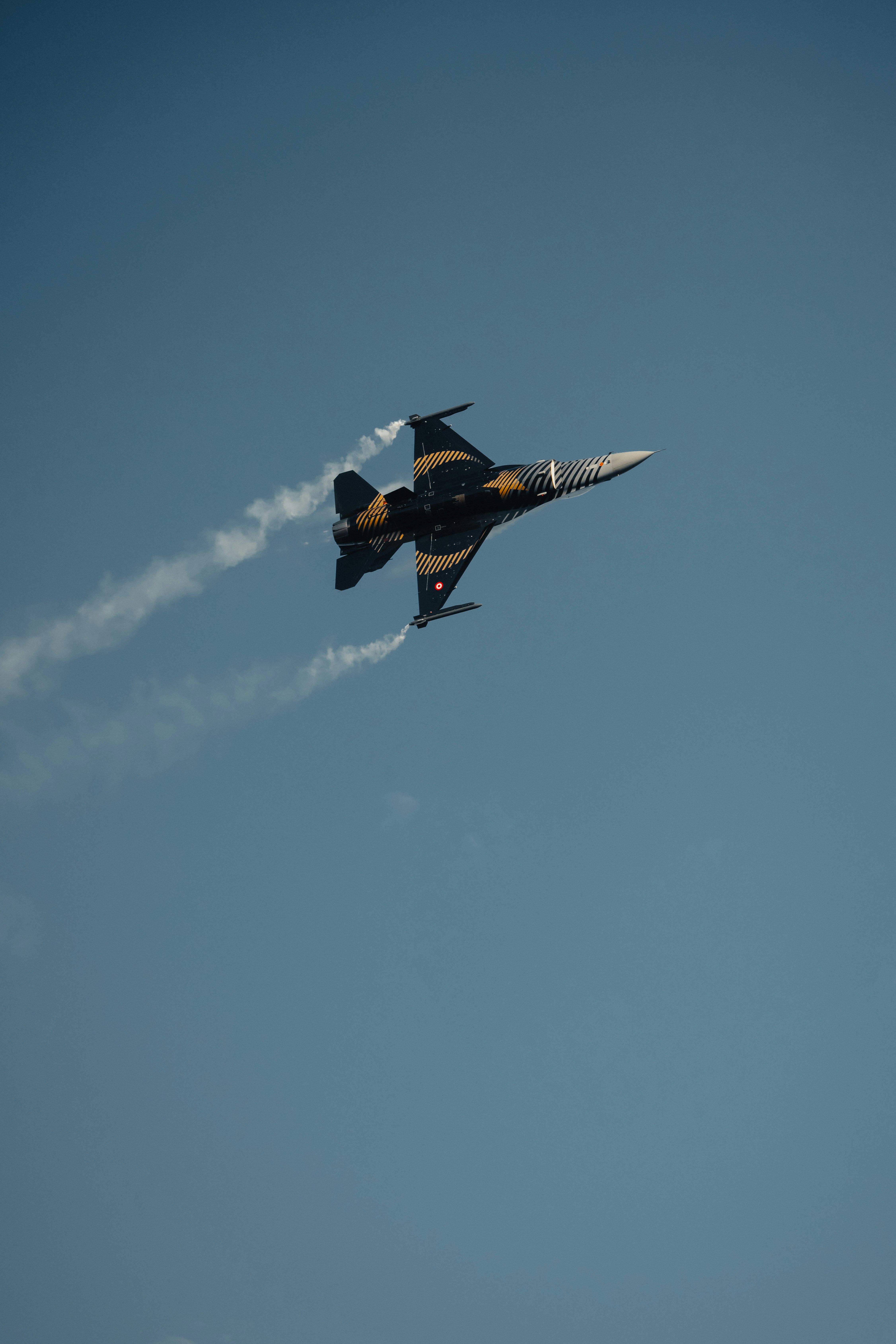 A fighter jet flying through a blue sky