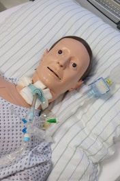 A dummy laying in a hospital bed with an oxygen tube attached to it