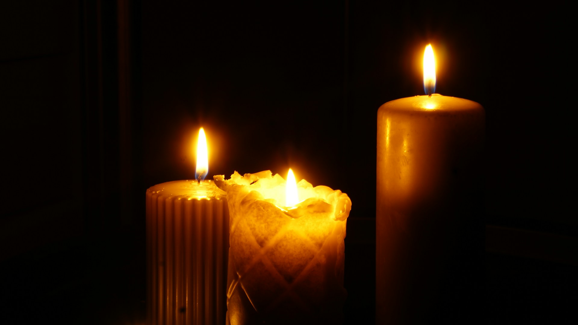 Three lit candles sitting next to each other