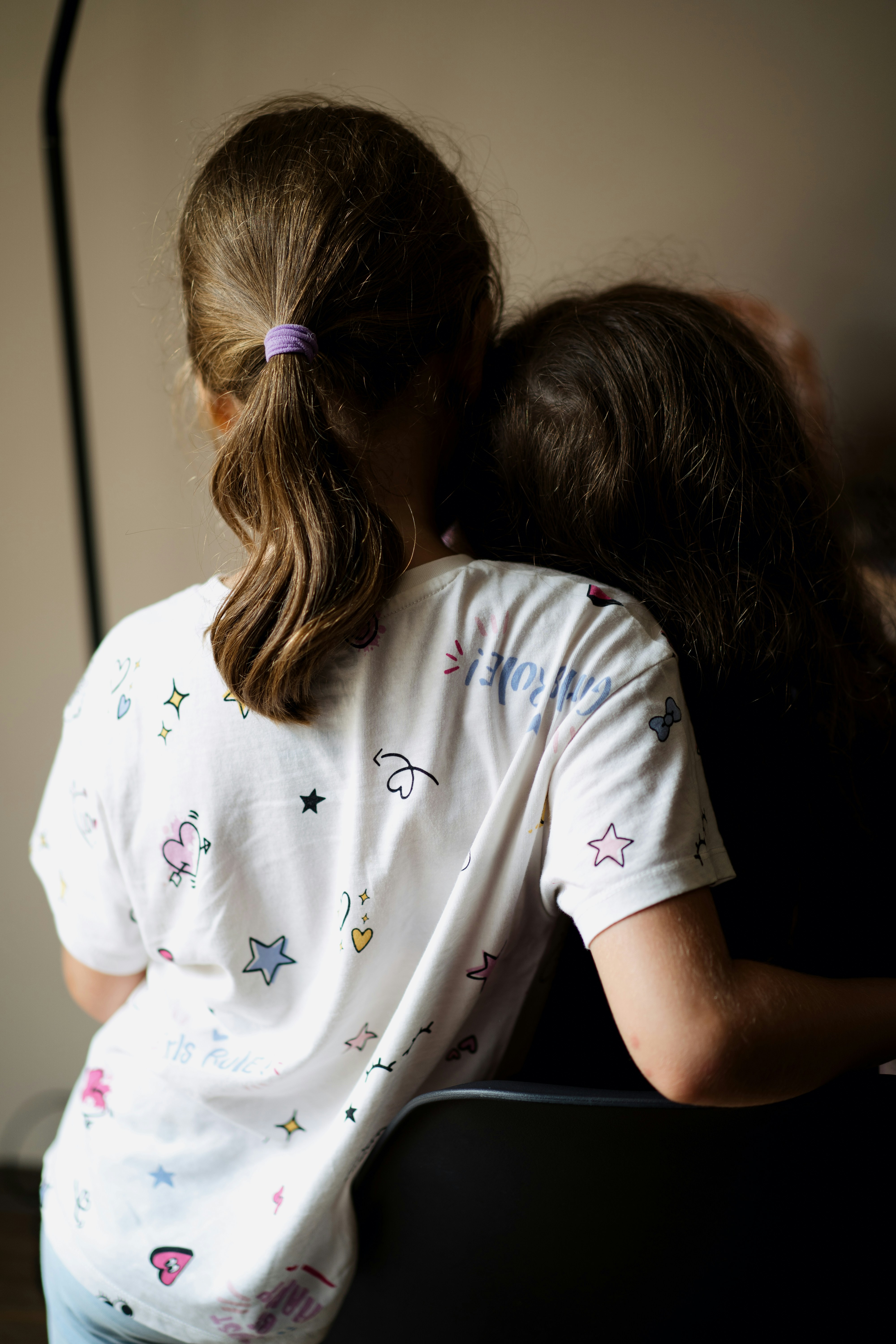 A little girl hugging a little girl sitting on a chair