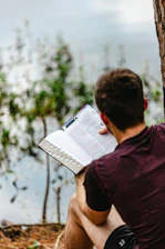 A man sitting on the ground reading a book
