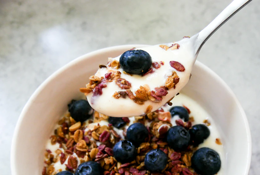 A bowl of granola with yogurt and blueberries