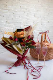 A basket of flowers next to a glass of wine