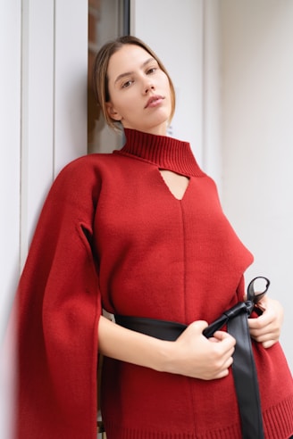 A woman wearing a red sweater and black pants