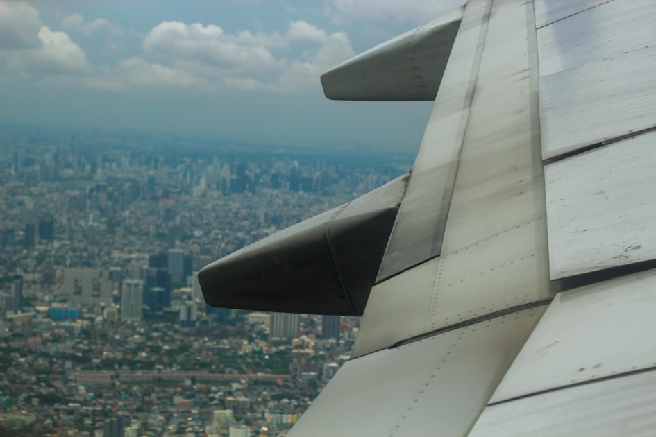 The wing of an airplane flying over a city