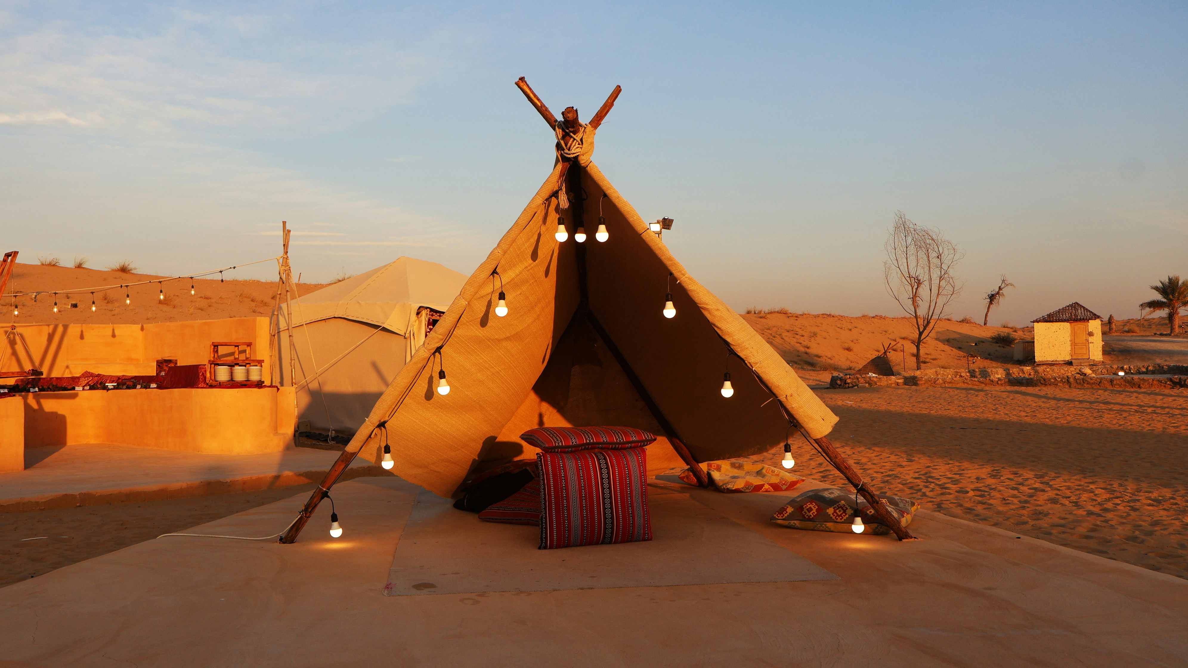 A teepee tent with lights in the middle of a desert, A bedouin tent in the middle of a desert