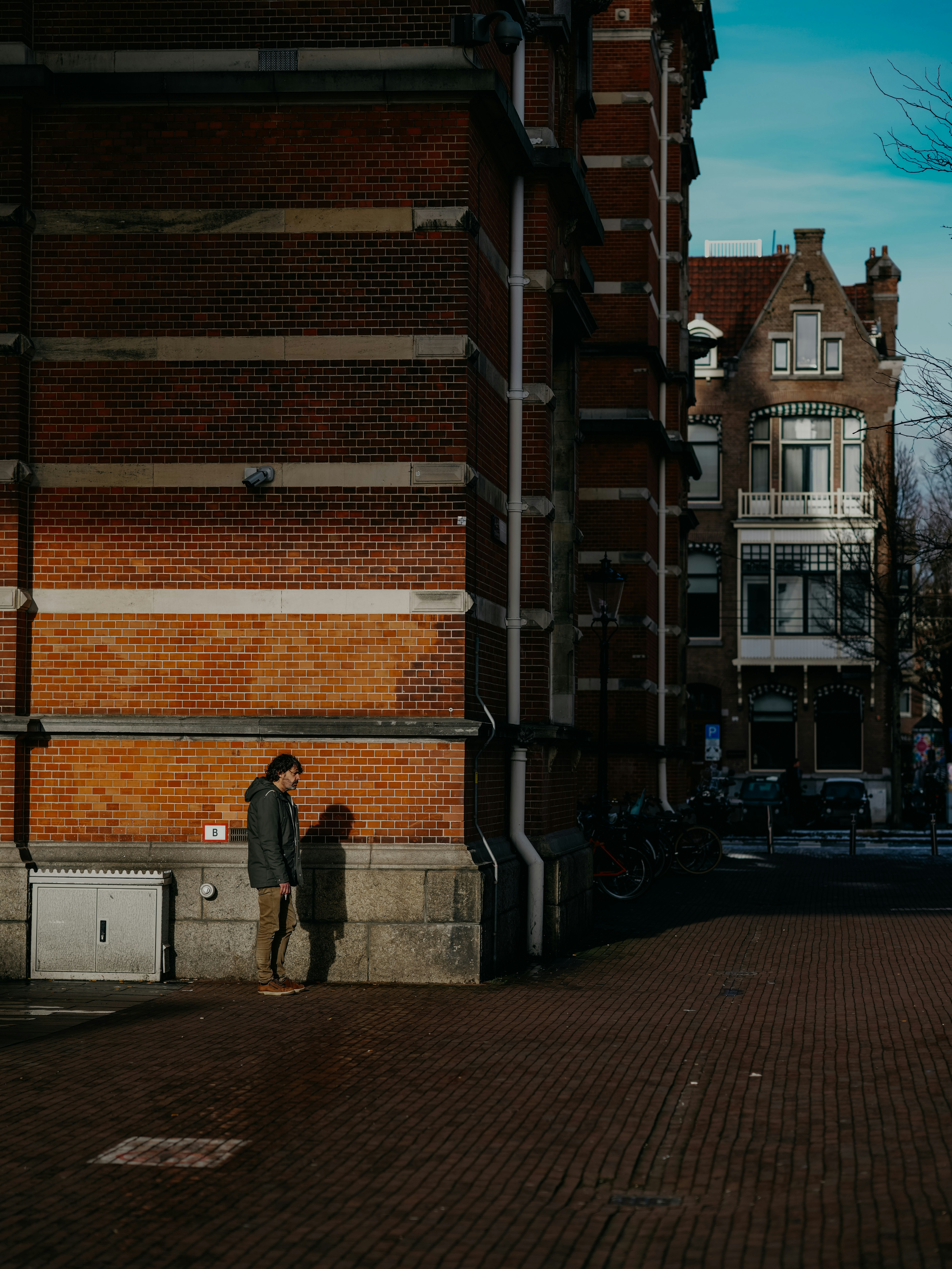 Una persona de pie en una acera de ladrillos junto a un edificio