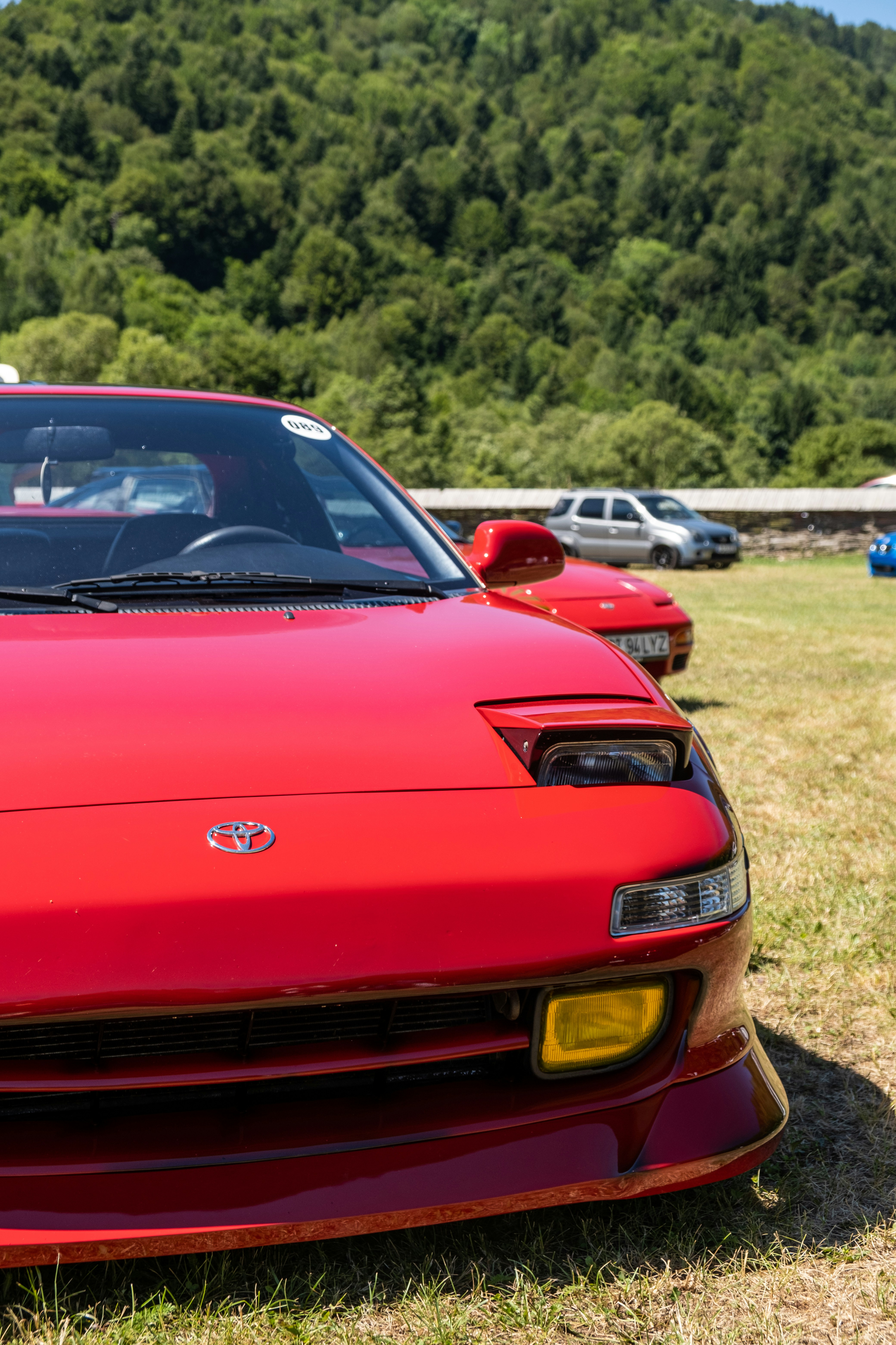 A red sports car parked on top of a grass covered field