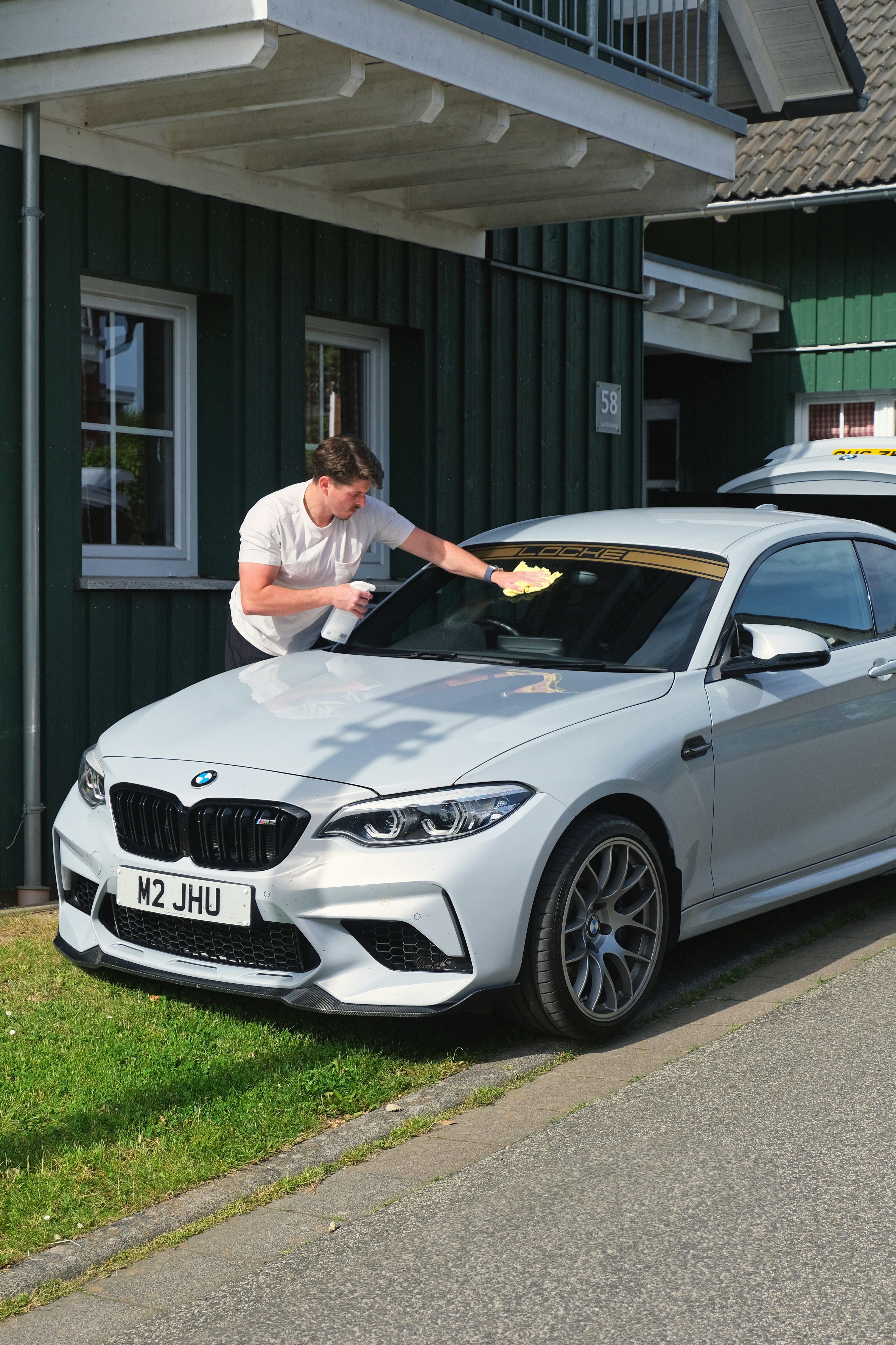 A man waxing the hood of a silver car
