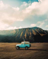 A blue truck is parked in the middle of a dirt field