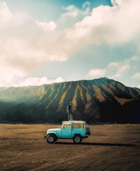 A blue truck is parked in the middle of a dirt field