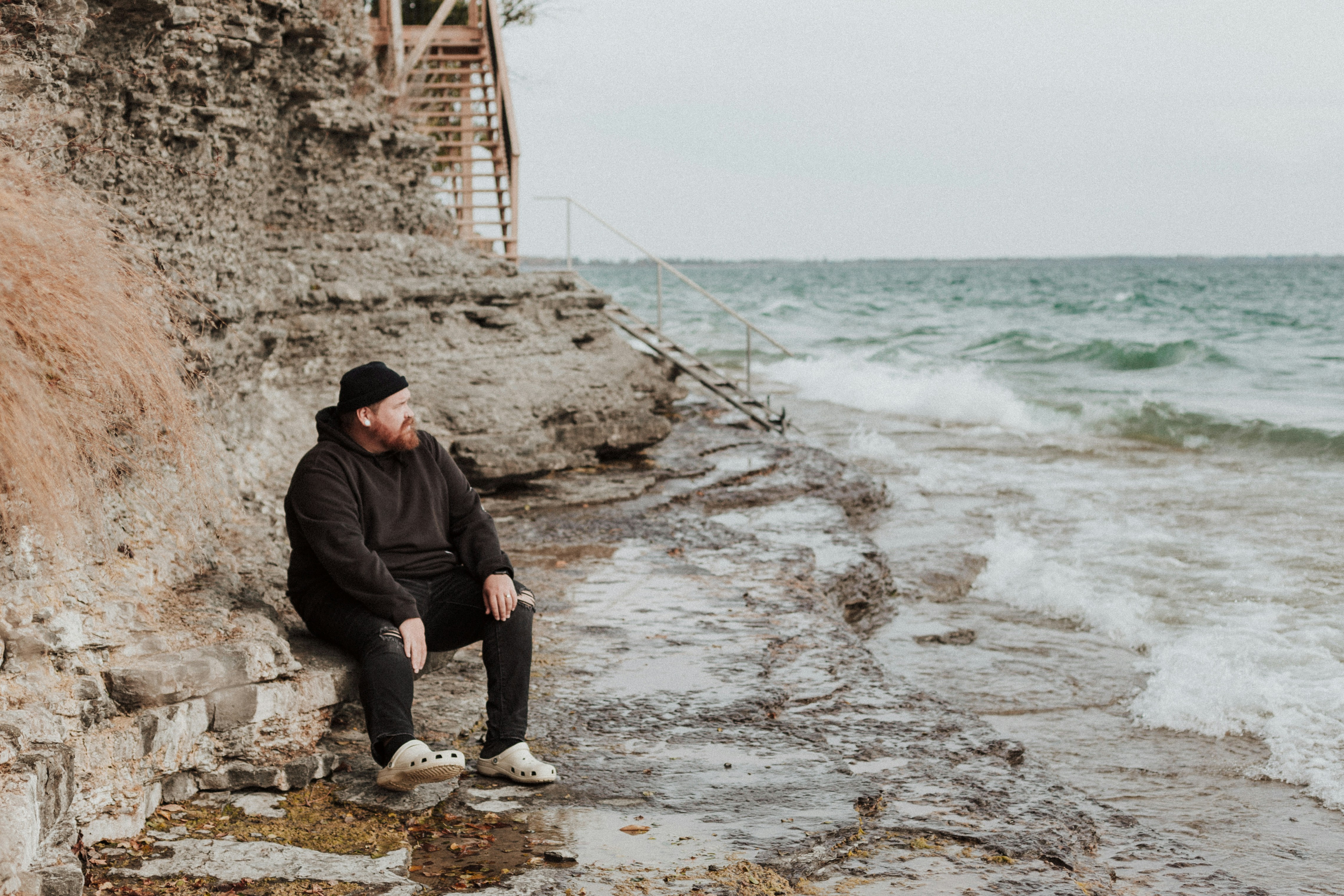 A man sitting on a rock next to the ocean