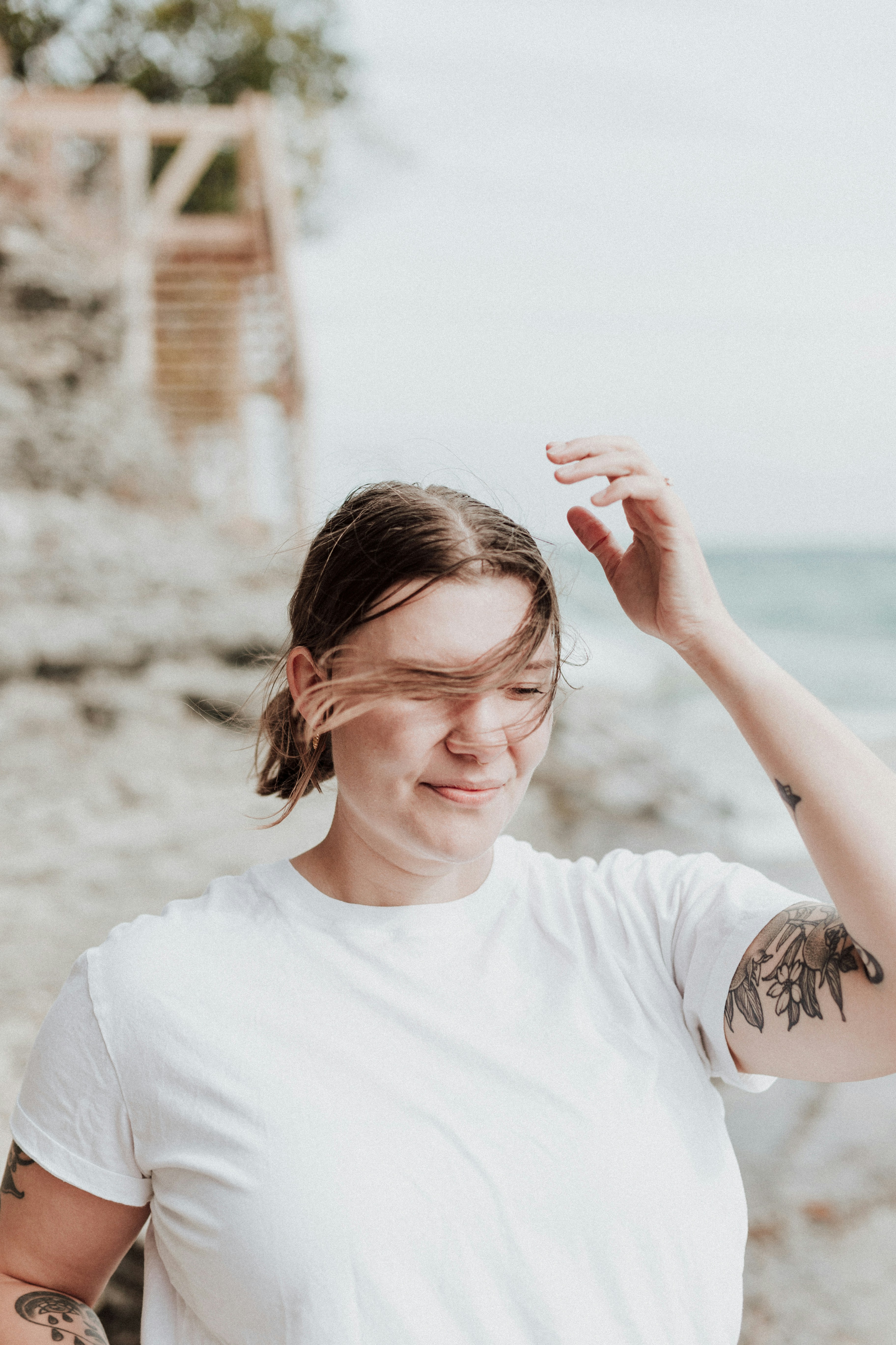 A woman with a tattoo on her arm standing on a beach